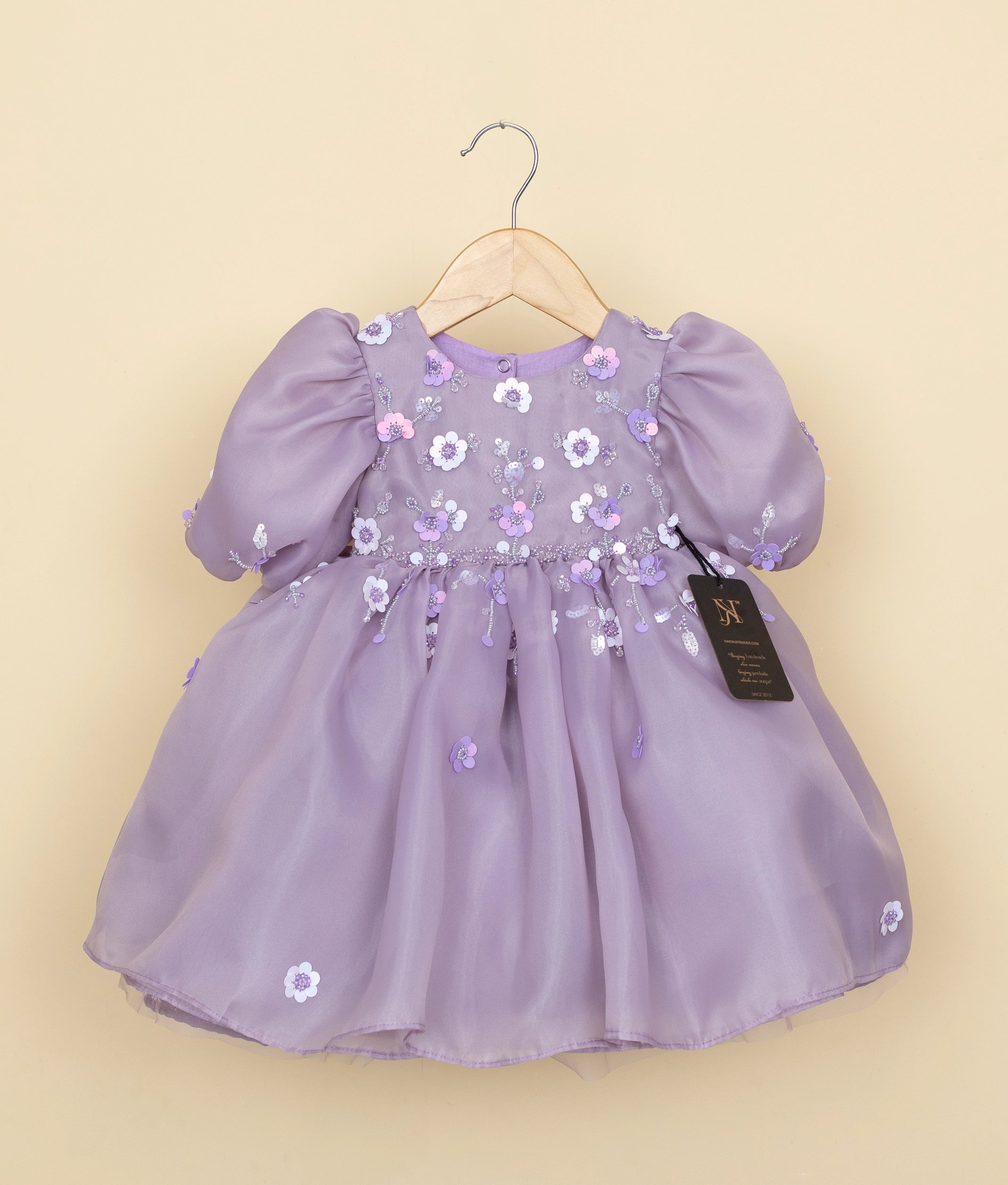 Front view of a pastel lavender organza girl's birthday frock with floral embroidery, beads, and balloon sleeves