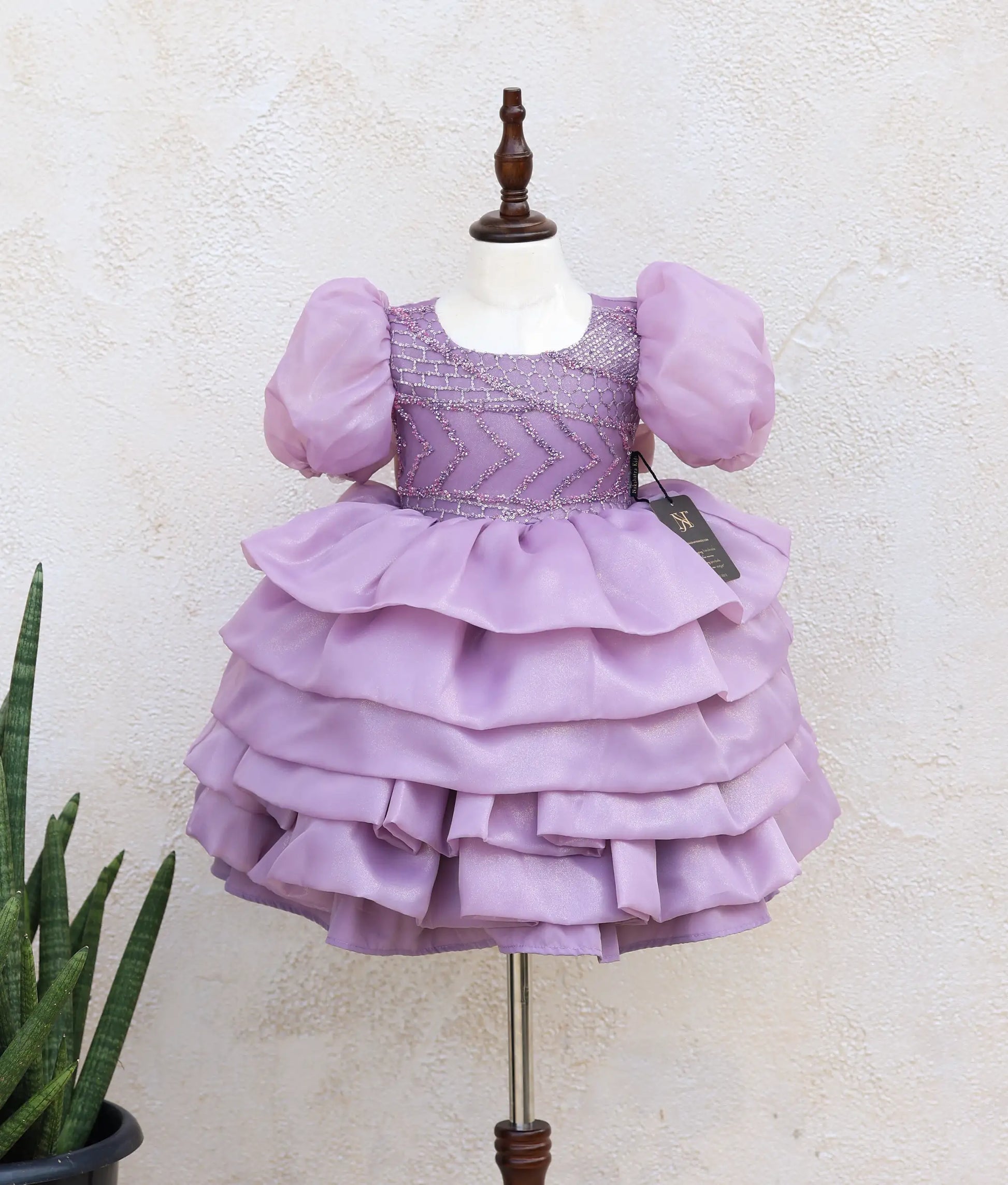 Front view of a pastel lavender shimmer organza princess theme dress for baby girls with ruffled layers