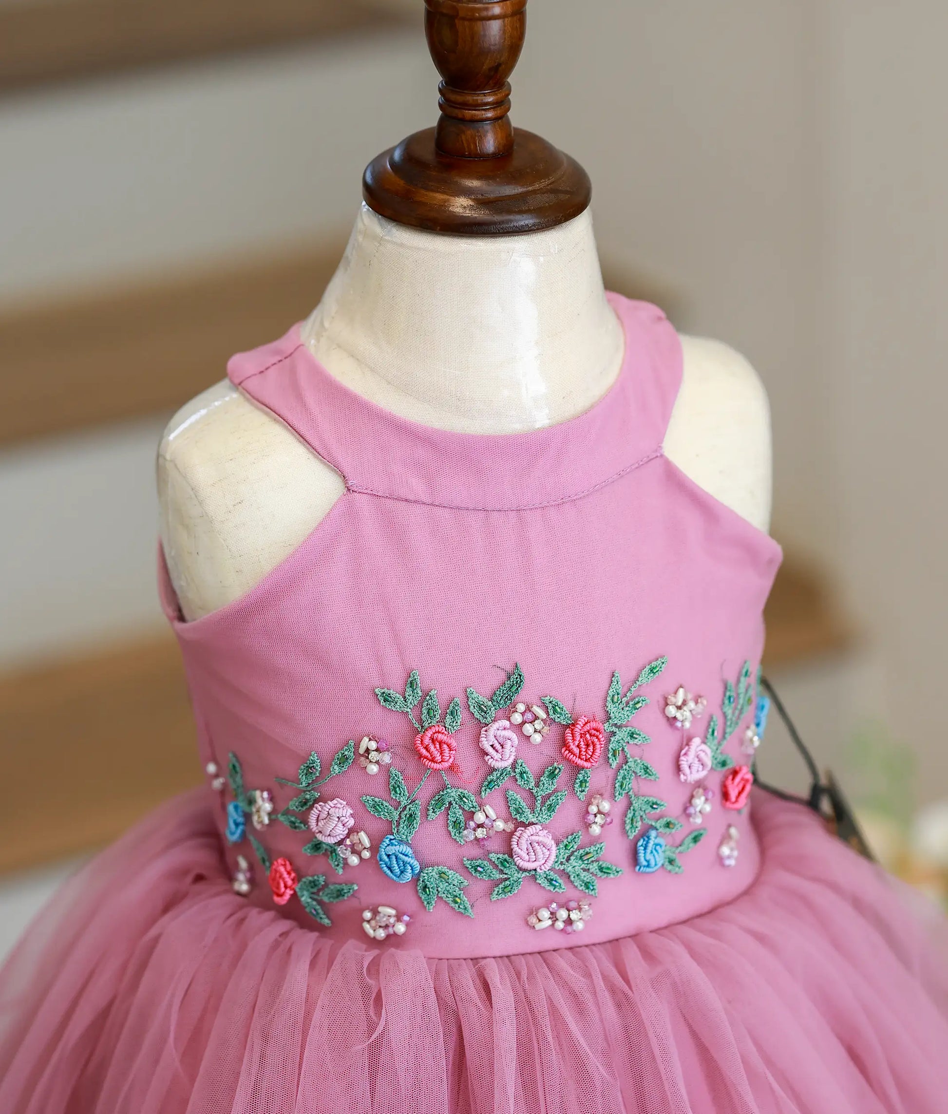 Close-up of the pastel lavender frock showing the intricate hand-stitched embellishments on the halter neckline.