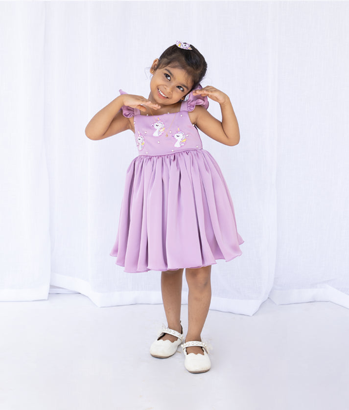 Front view of a pastel lavender unicorn theme baby girl dress with a flared skirt and ruffle details