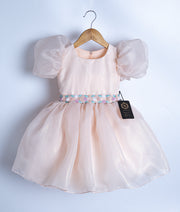 Front view of a pastel peach satin organza birthday frock for baby girls with floral embroidery and balloon sleeves