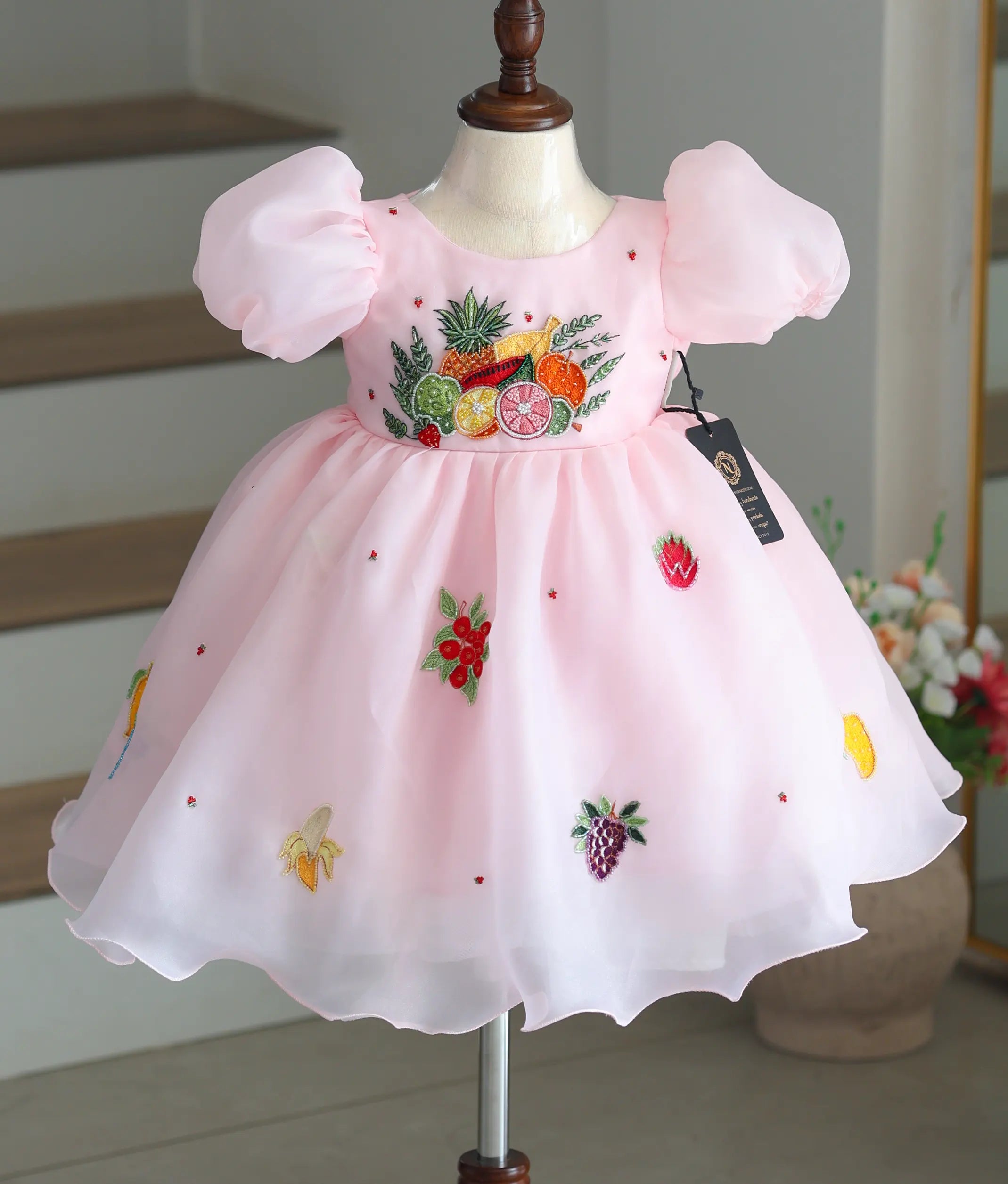 Front view of a pastel pink crush organza frock with fruit-themed handwork.