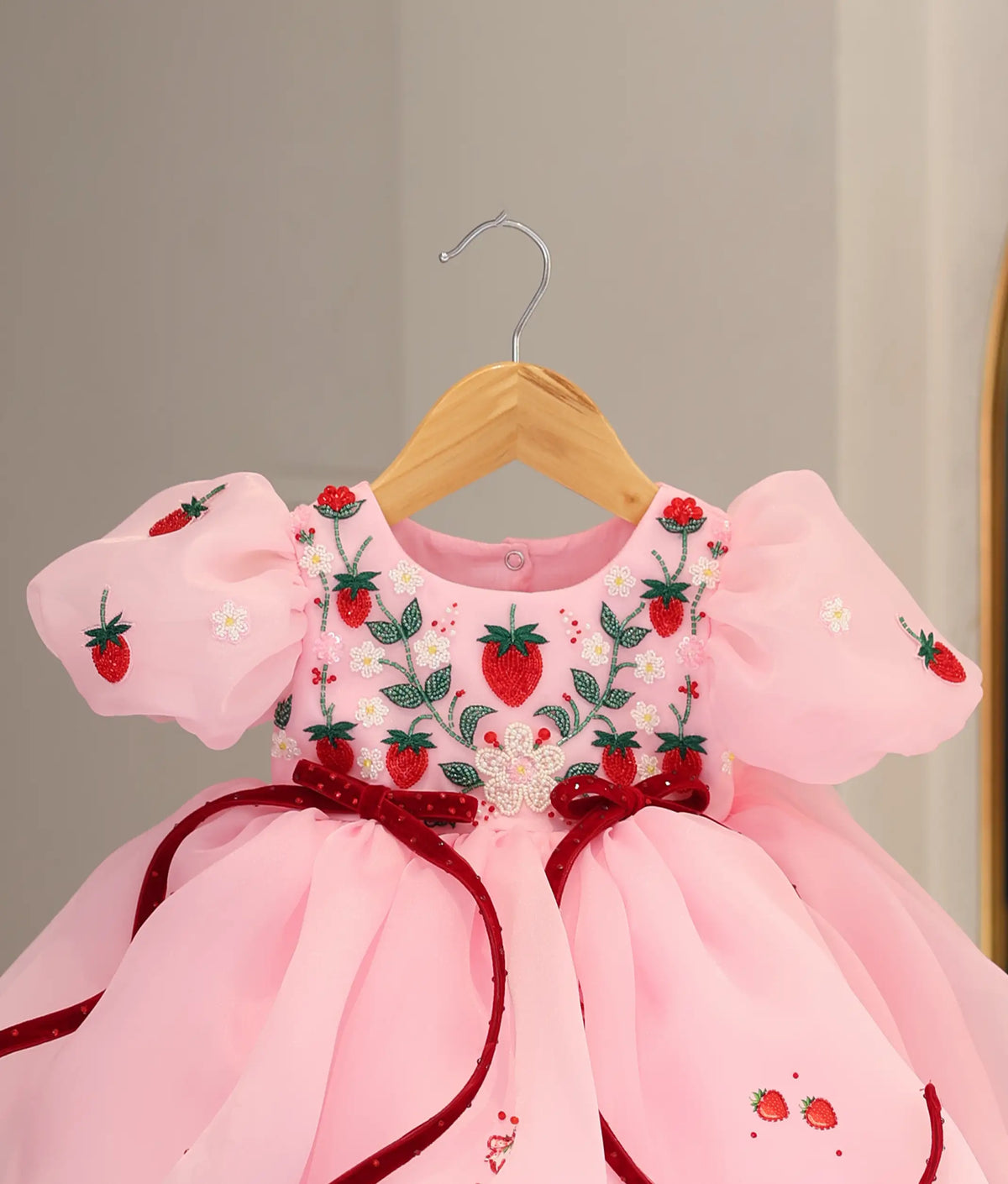 Close-up view of pastel pink frock top showing strawberry beadwork and short puff sleeves.