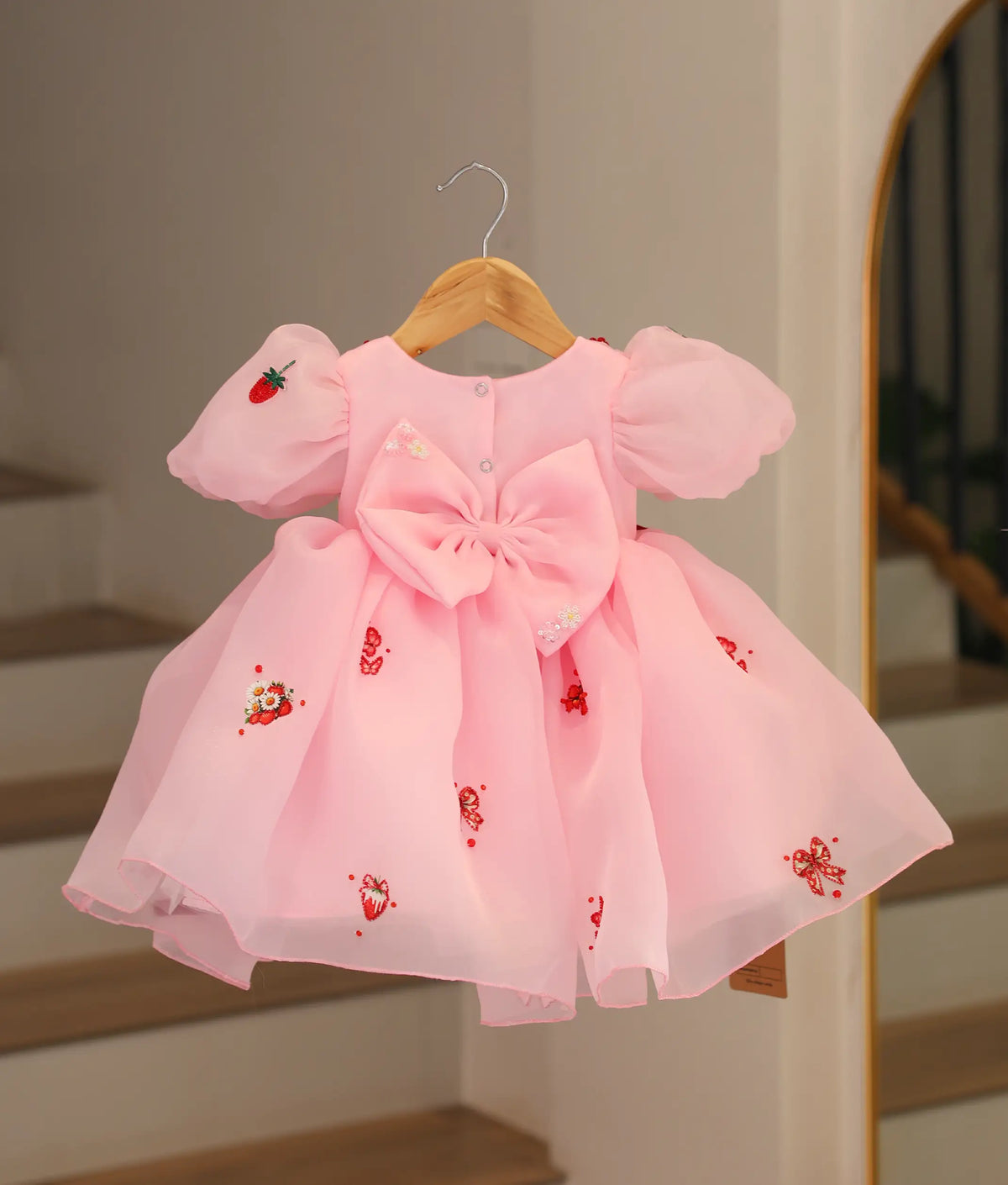 Back view of pastel pink strawberry theme frock showing back buttons and big bow.