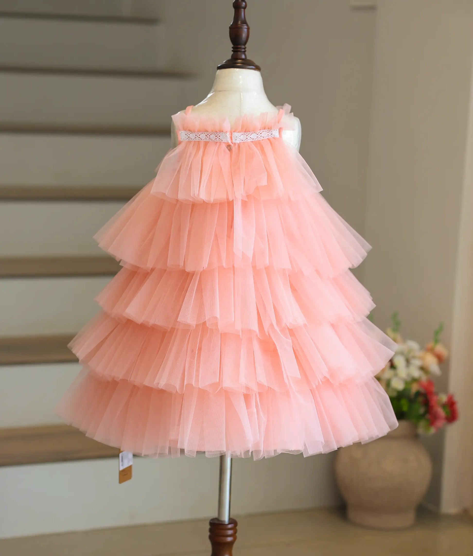 Back view of the peach birthday frock showing the square neck and press button closure.