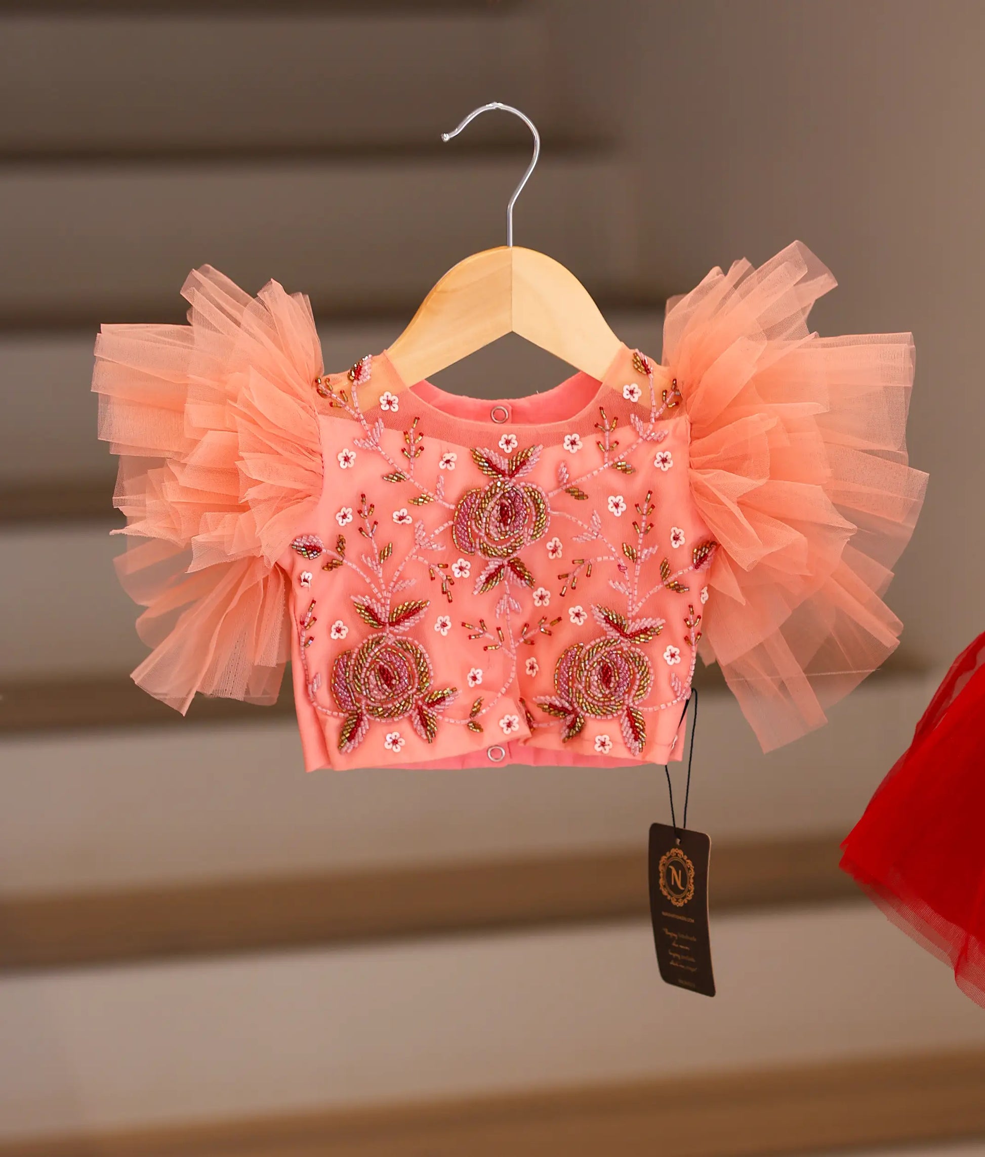 Close-up of the peach top showing the detailed floral embroidery, beadwork, and butterfly sleeves