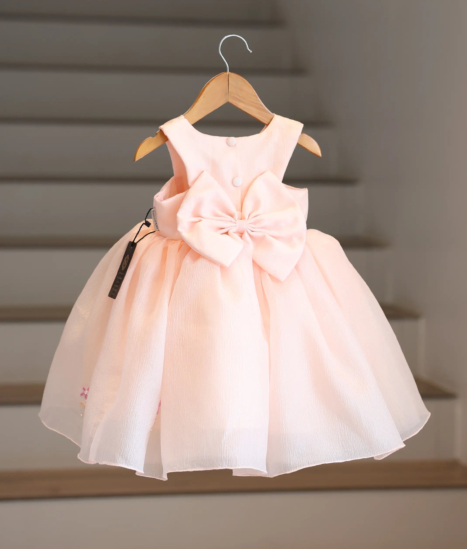 Back view of the pastel peach frock showing the button closure and the big bow.