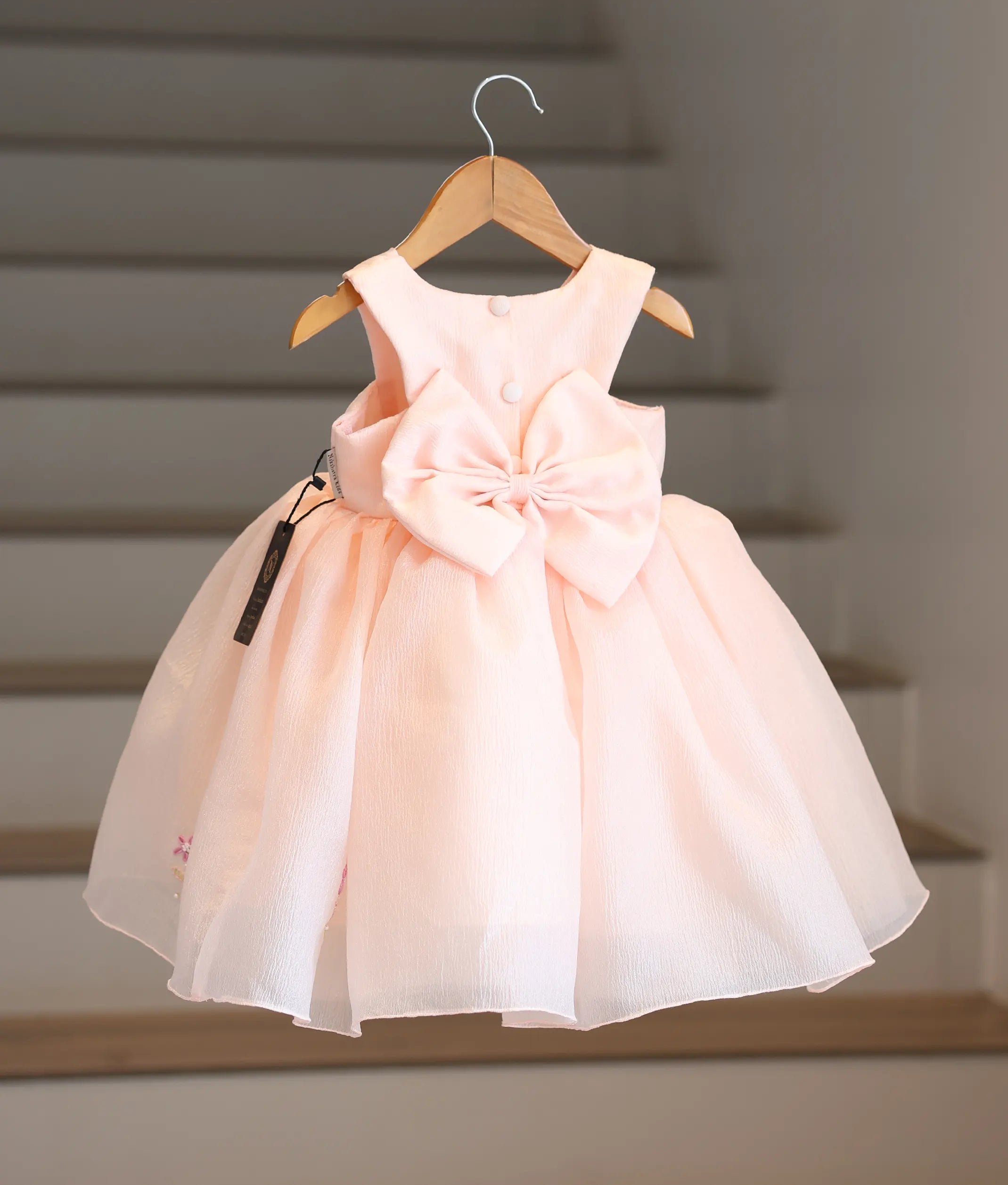 Back view of the pastel peach frock showing the button closure and the big bow.