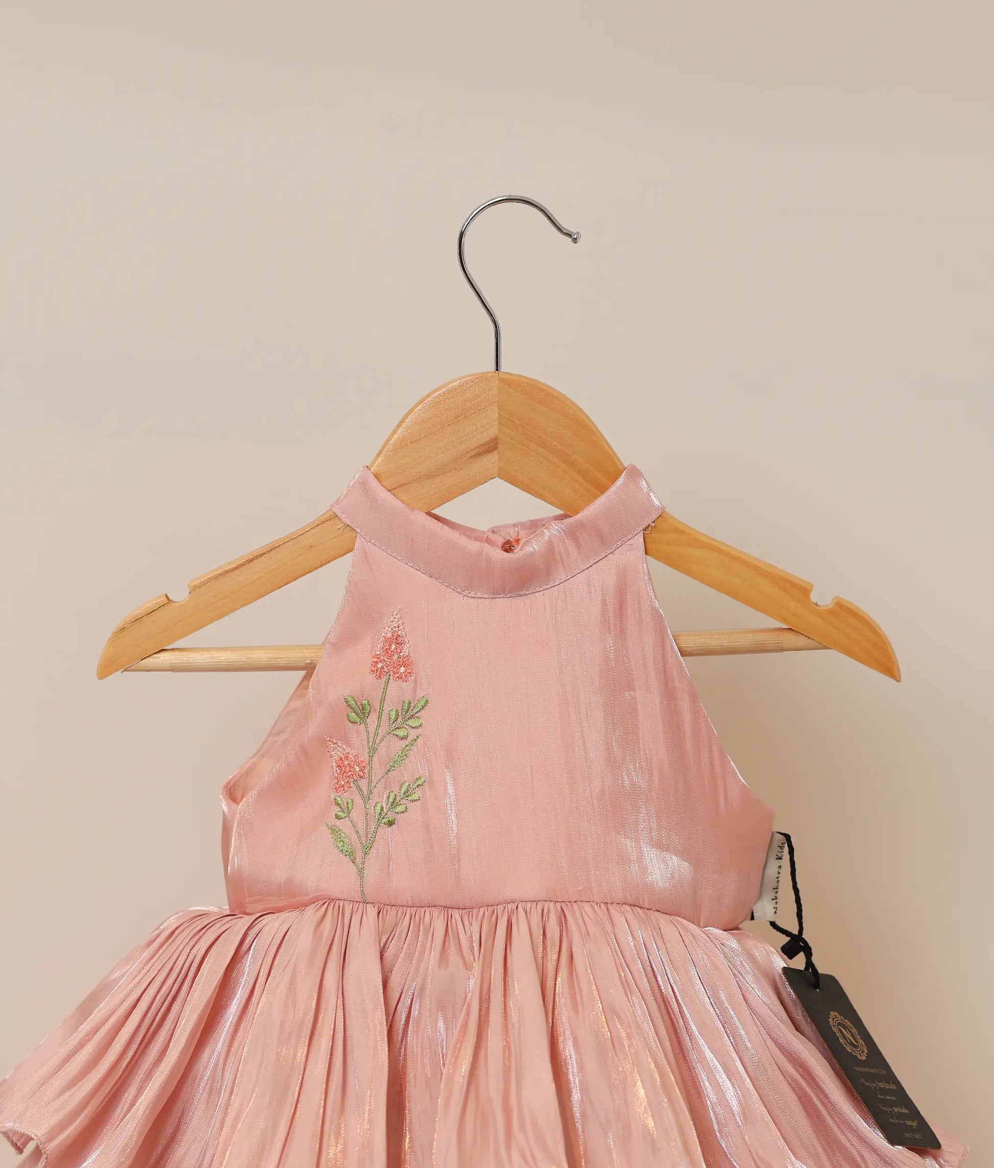 Close-up of the shimmering peach lacer organza fabric and the delicate floral embroidery on the halter-neck yoke