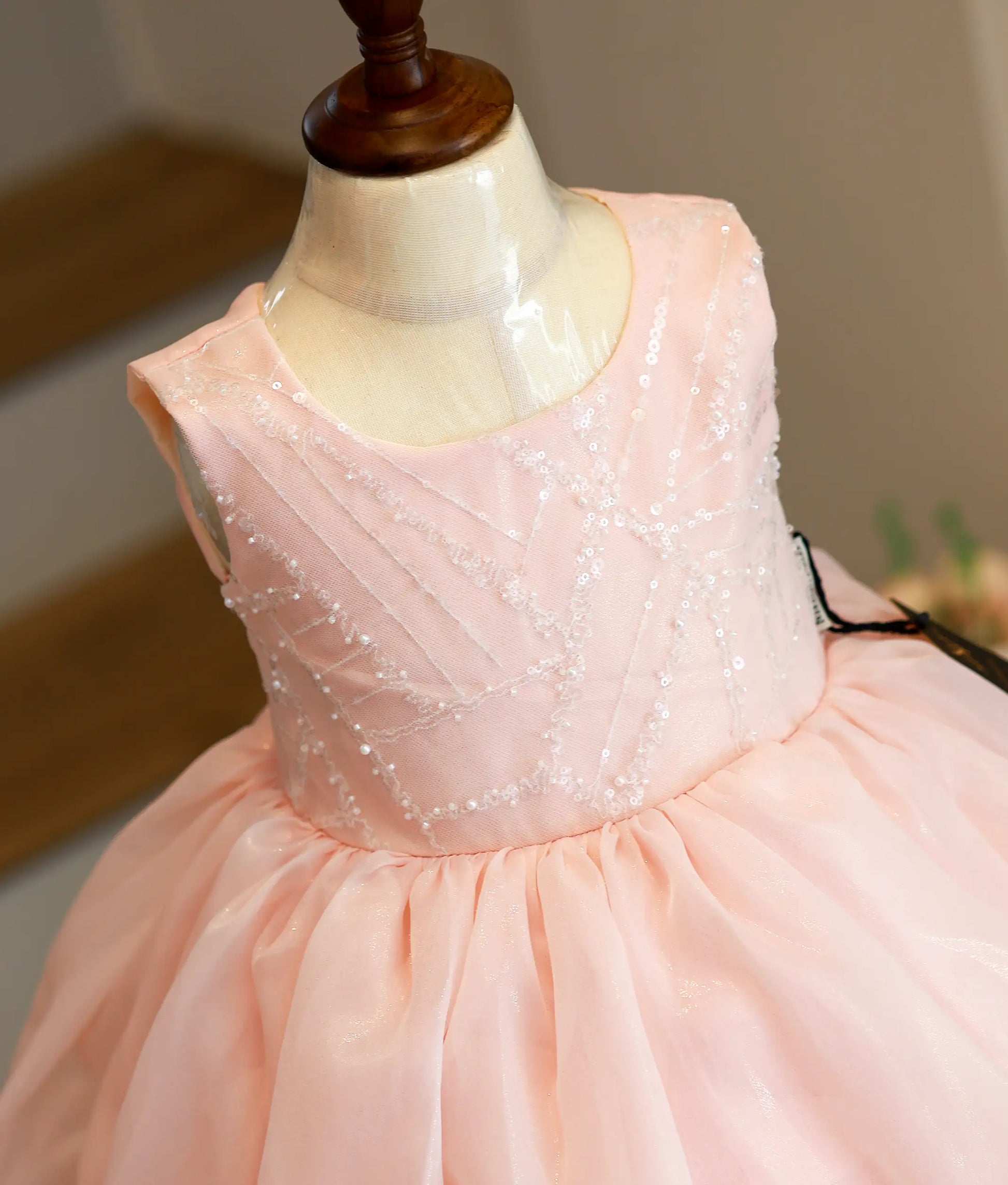 Close-up of the shimmering peach organza fabric and intricate white lace detailing on the scalloped hemline