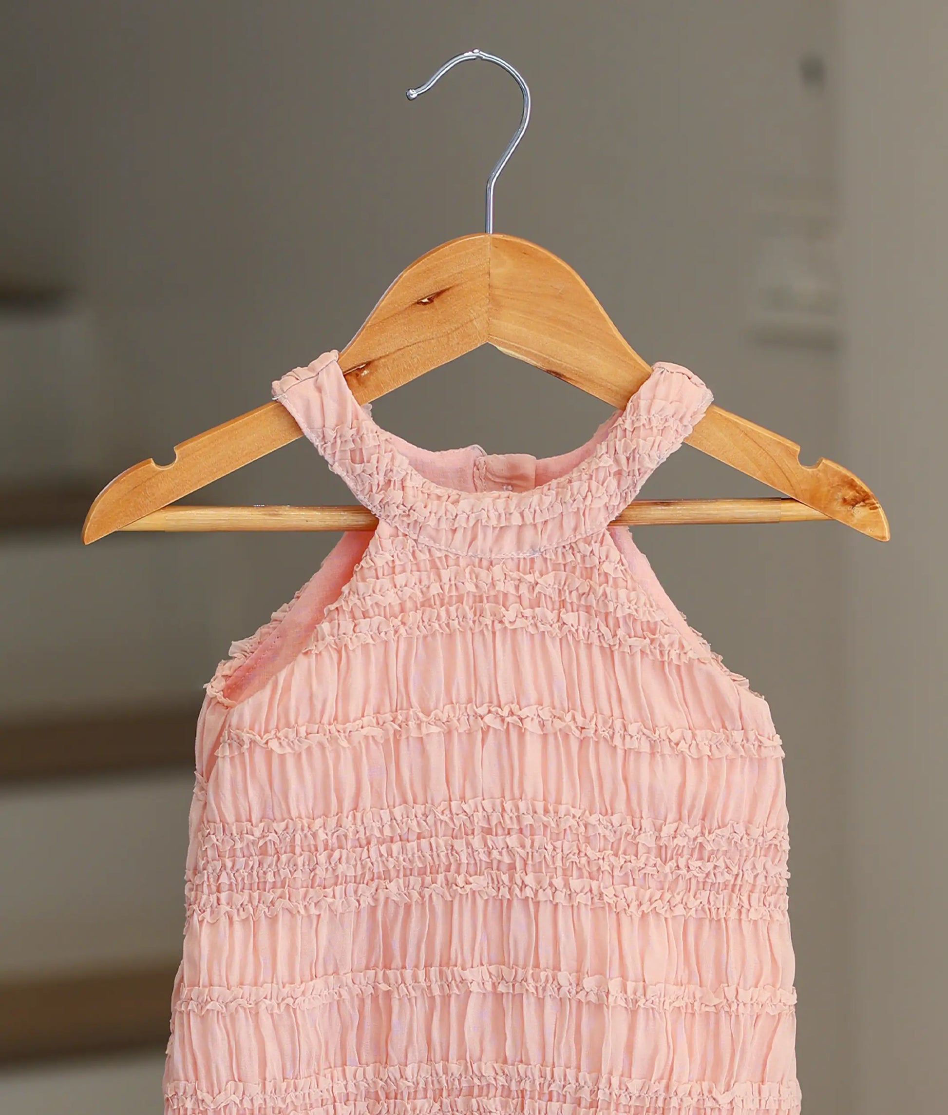 Close-up of the horizontal ruffled tiers and halter neck design on the peach georgette fabric.