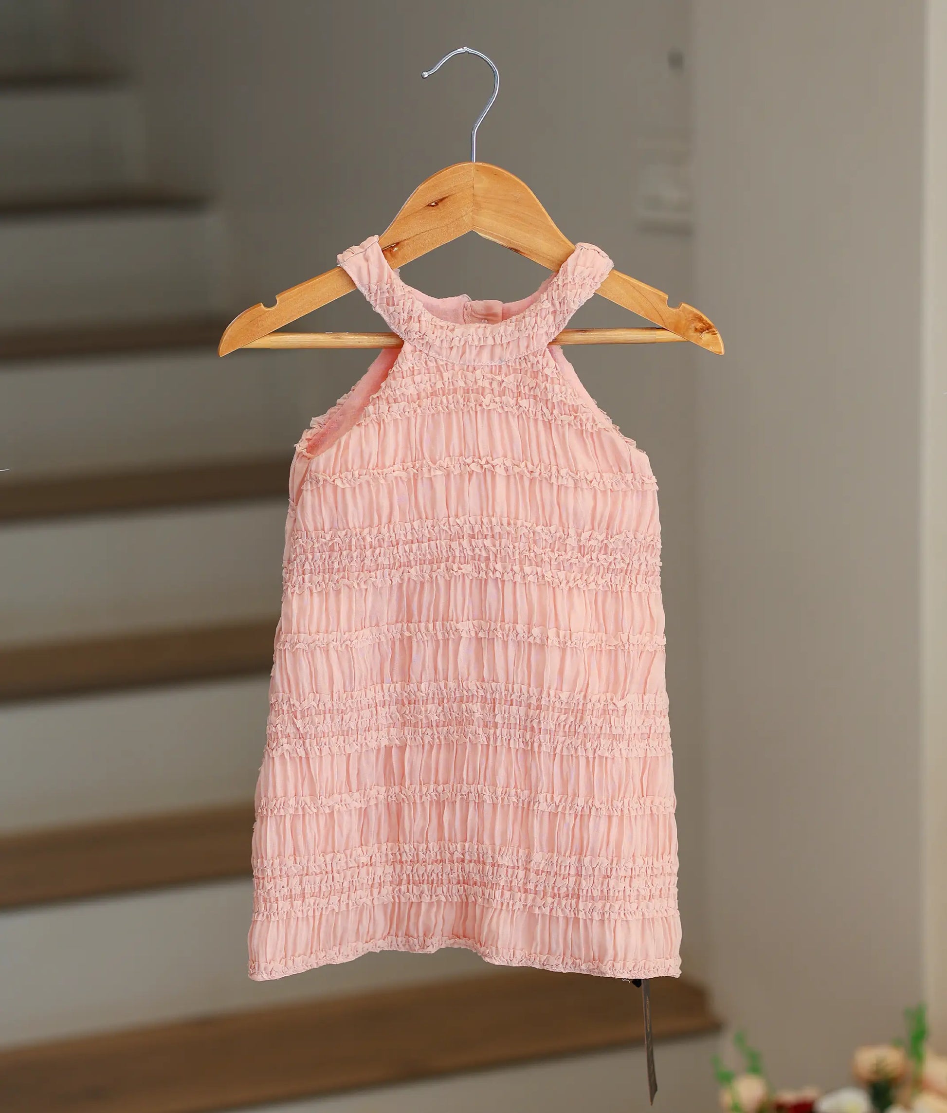 Front view of a peach georgette A-line birthday frock for baby girls featuring a tiered ruffle halter neck.