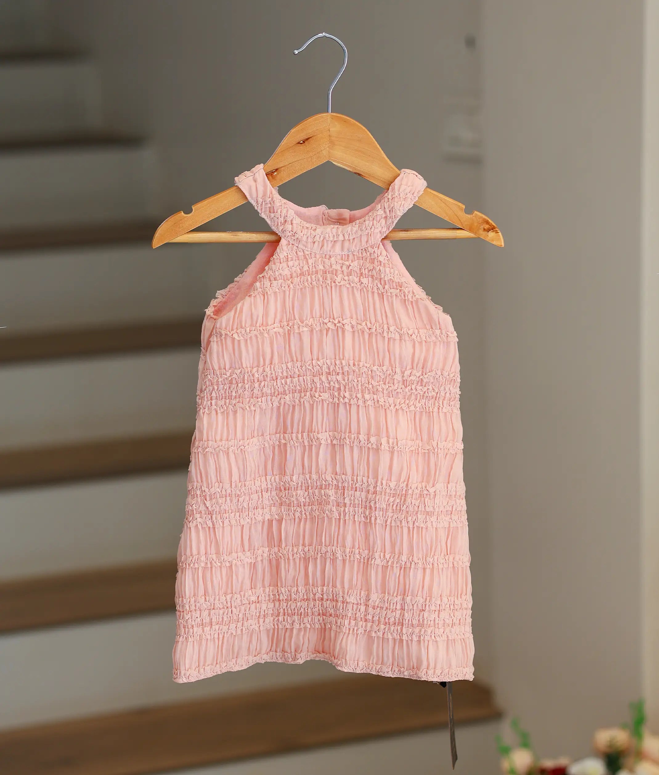 Front view of a peach georgette A-line birthday frock for baby girls featuring a tiered ruffle halter neck.