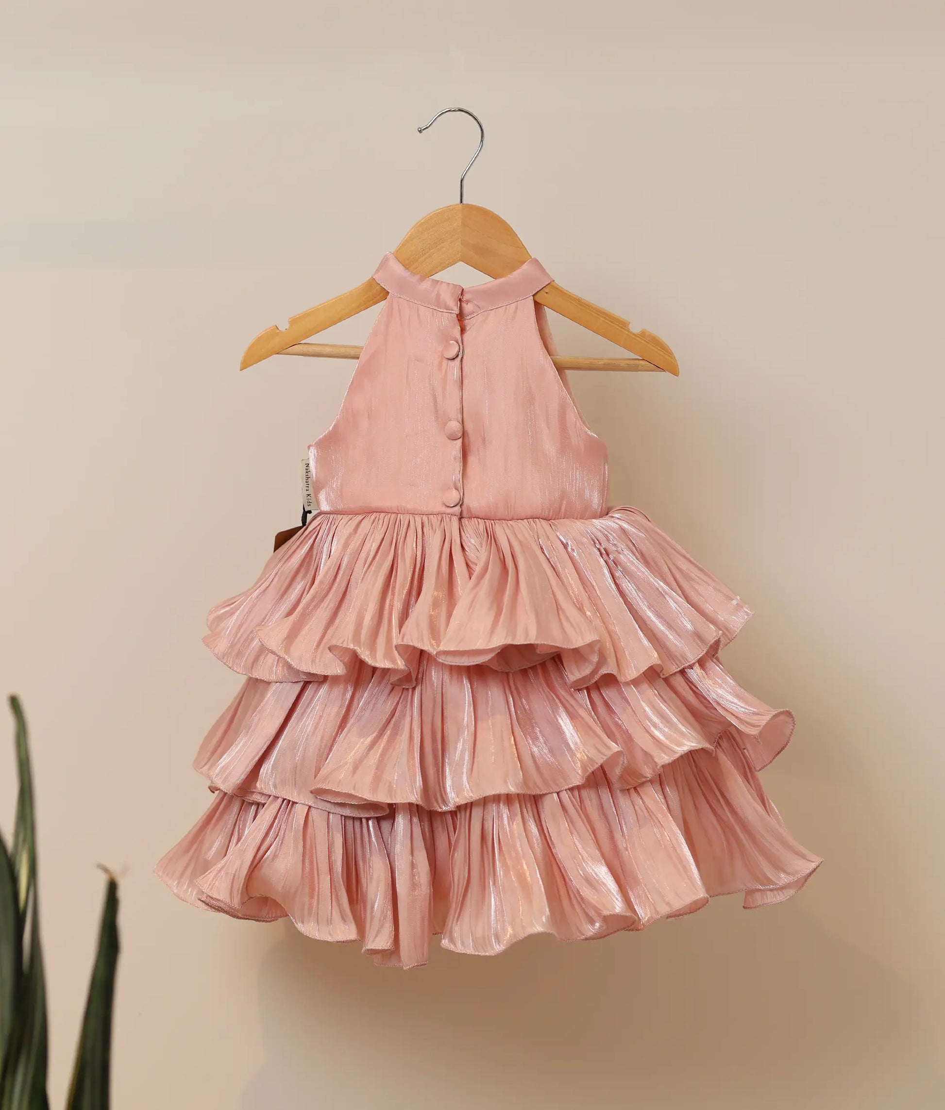 Back view of peach organza tiered dress showing the halter-neck with show button and the voluminous step-by-step ruffles