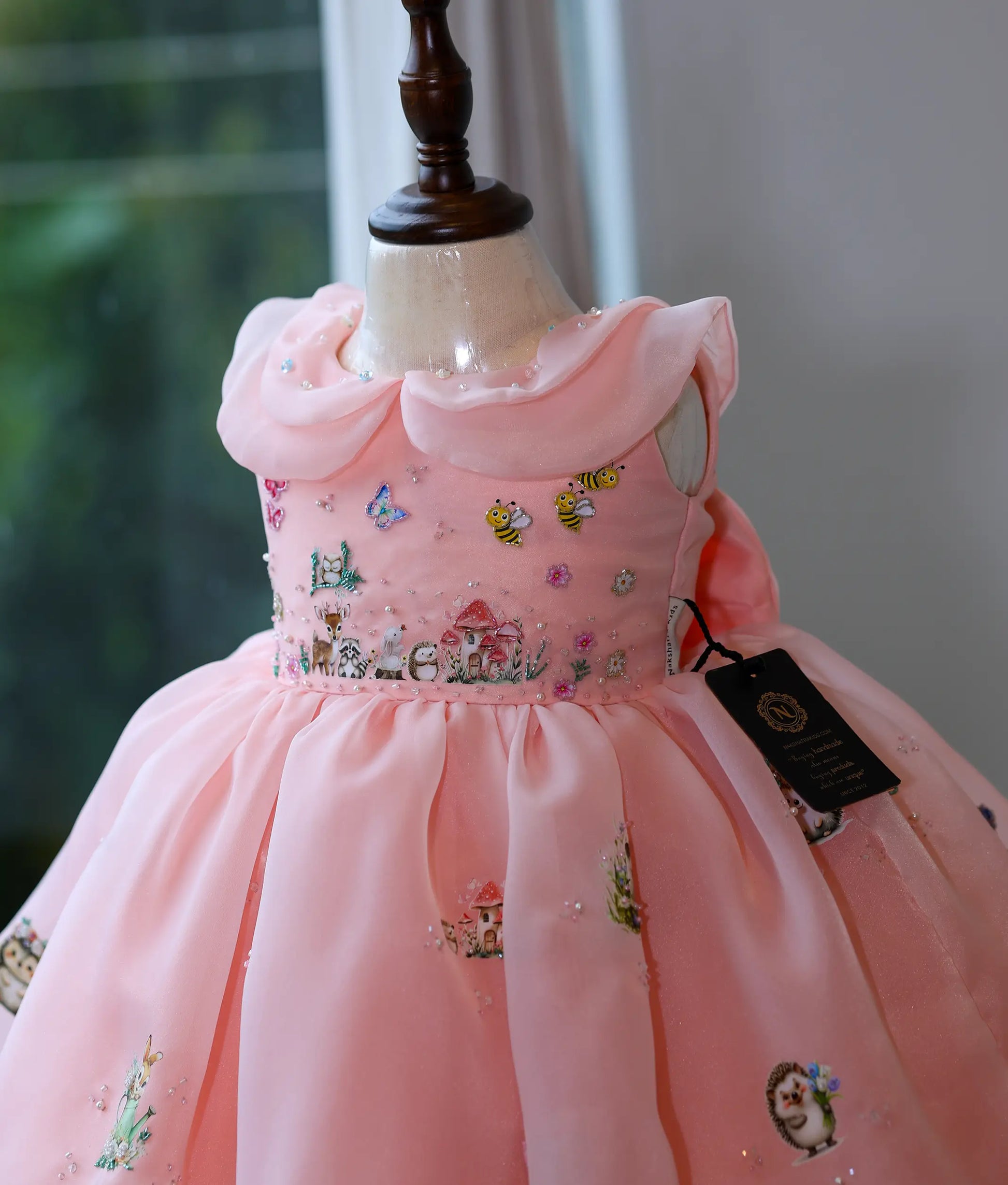 Close-up of bodice featuring printed woodland animals with pearl and bead handwork details.