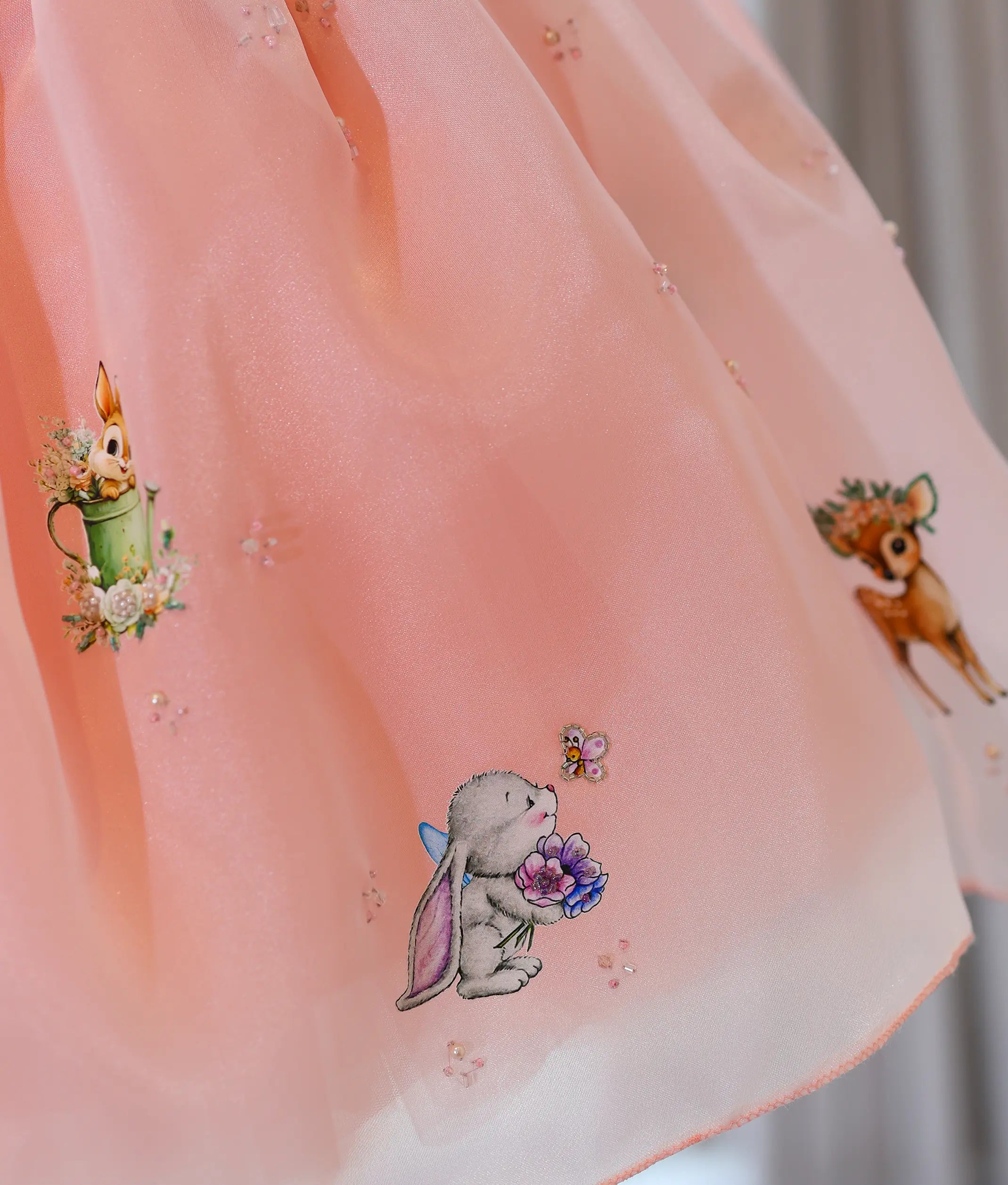 Close-up of organza skirt flare with printed woodland animals and sequin embellishments