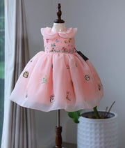 Peach pink plain organza handworked woodland theme frock for baby girl on a mannequin.