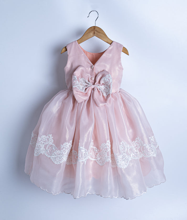 Back view of peach frock showing the elegant V-neck design and a large decorative bow with lacework