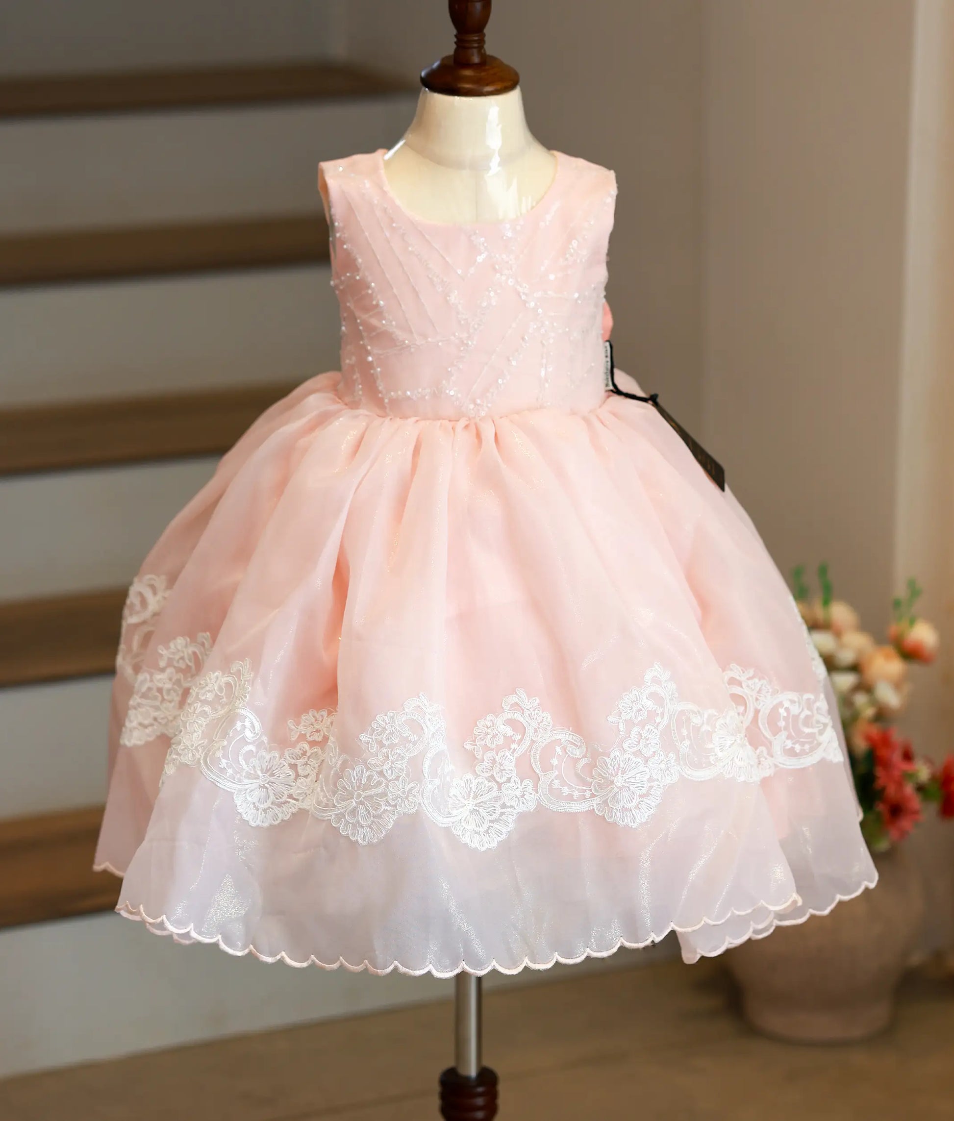 Front view of a peach shimmer organza birthday frock for girls with an embroidered waistline belt