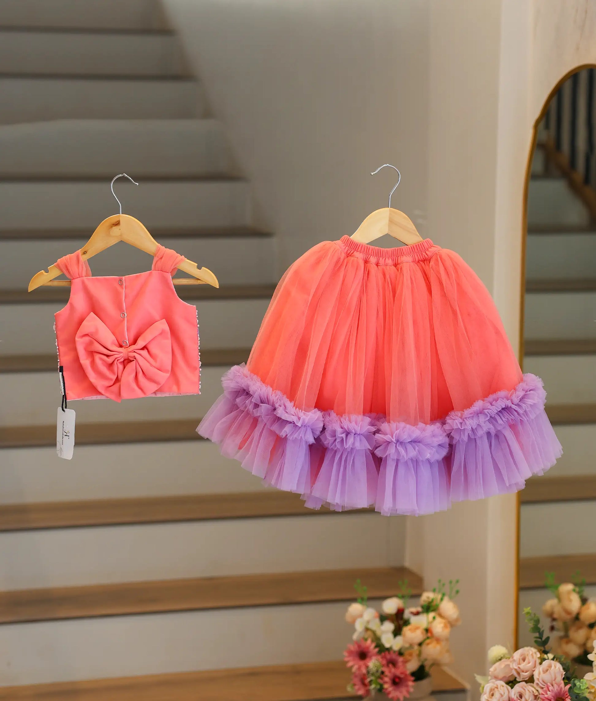 Back view of the peach crop top and skirt showing the square neck, press button closure, and decorative bow