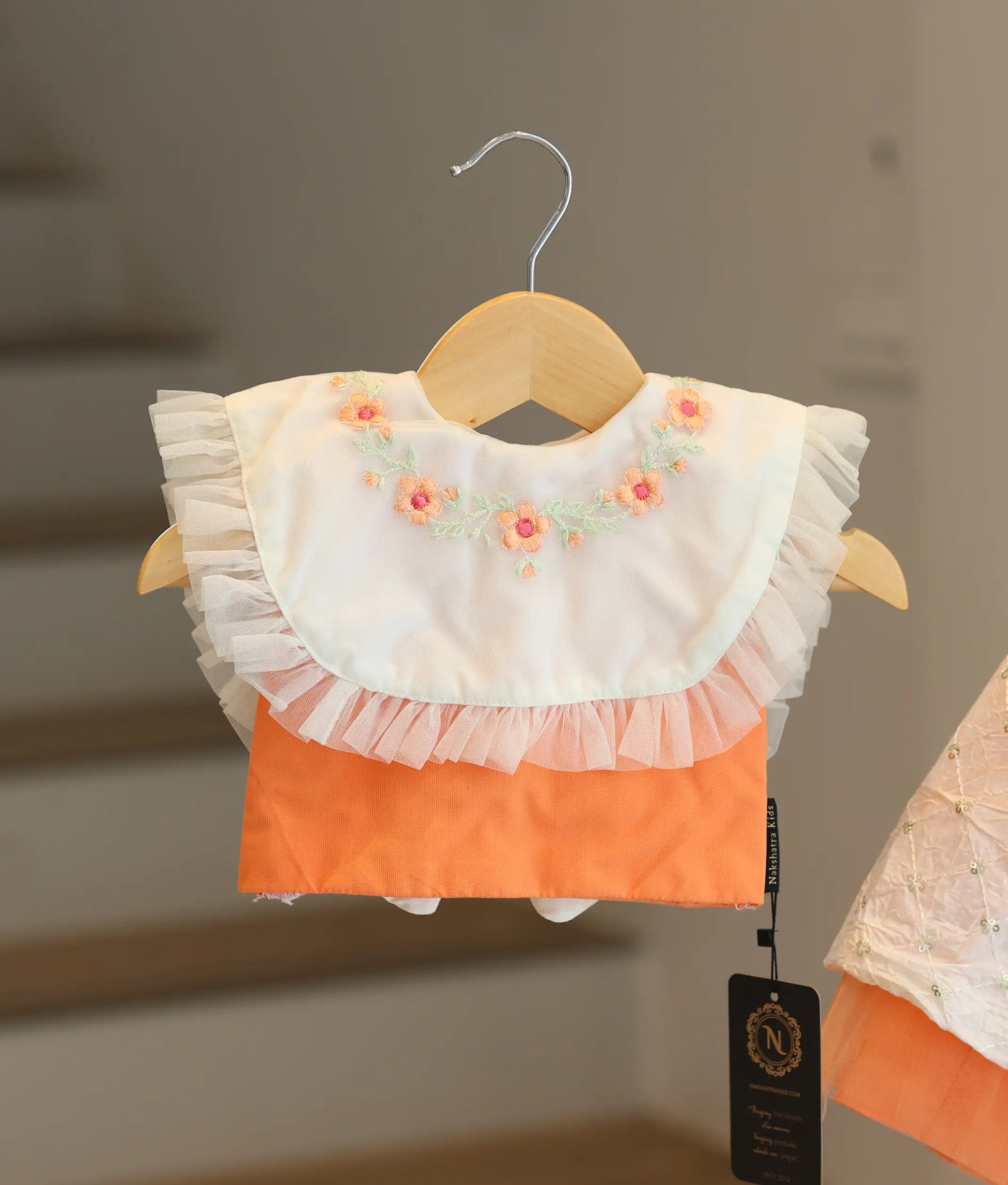 Close-up of the peach top showing the white collar with pleated net edges and delicate floral handwork