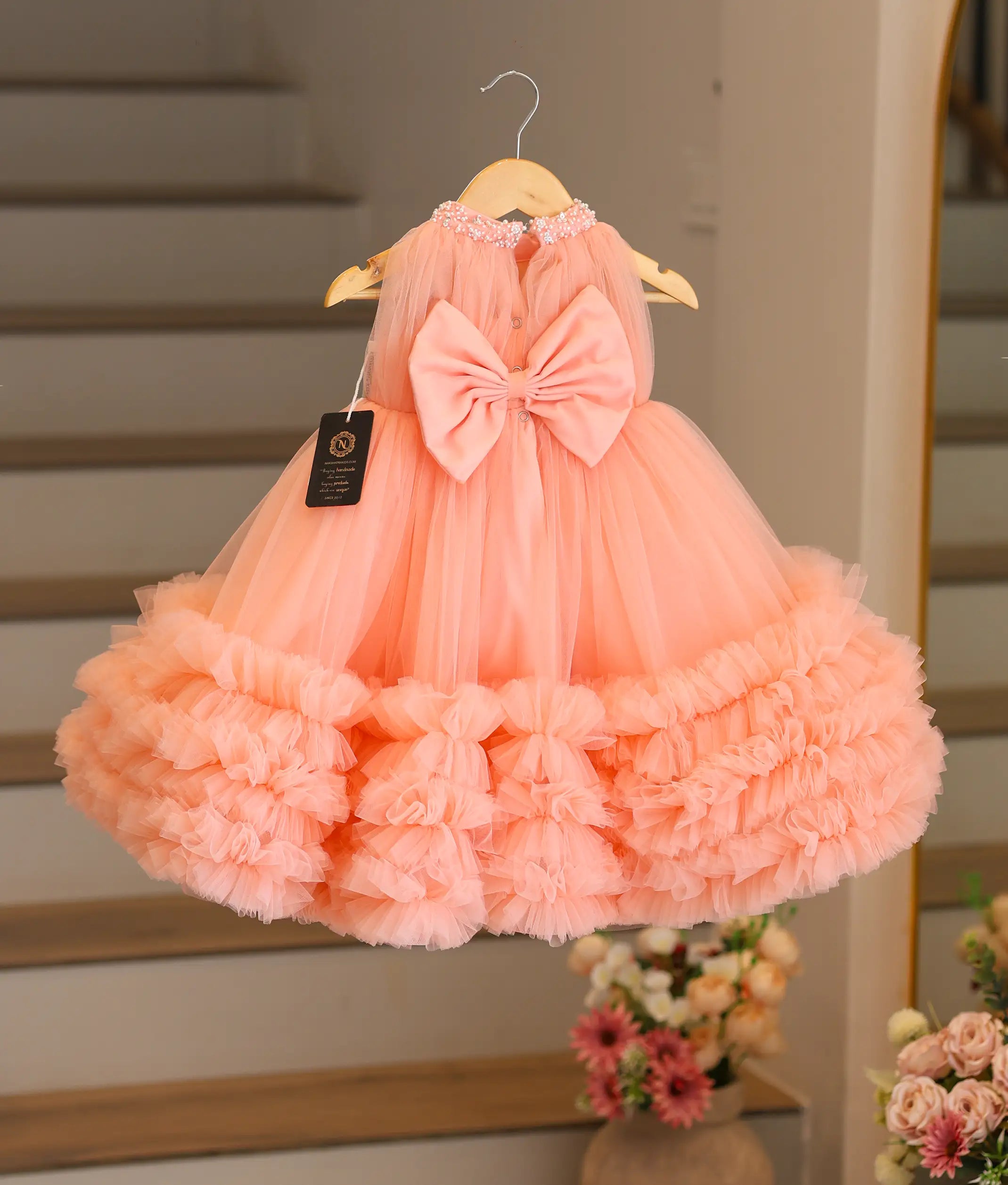 Back view of the peach tulle gown showing the large decorative bow and the round neckline.