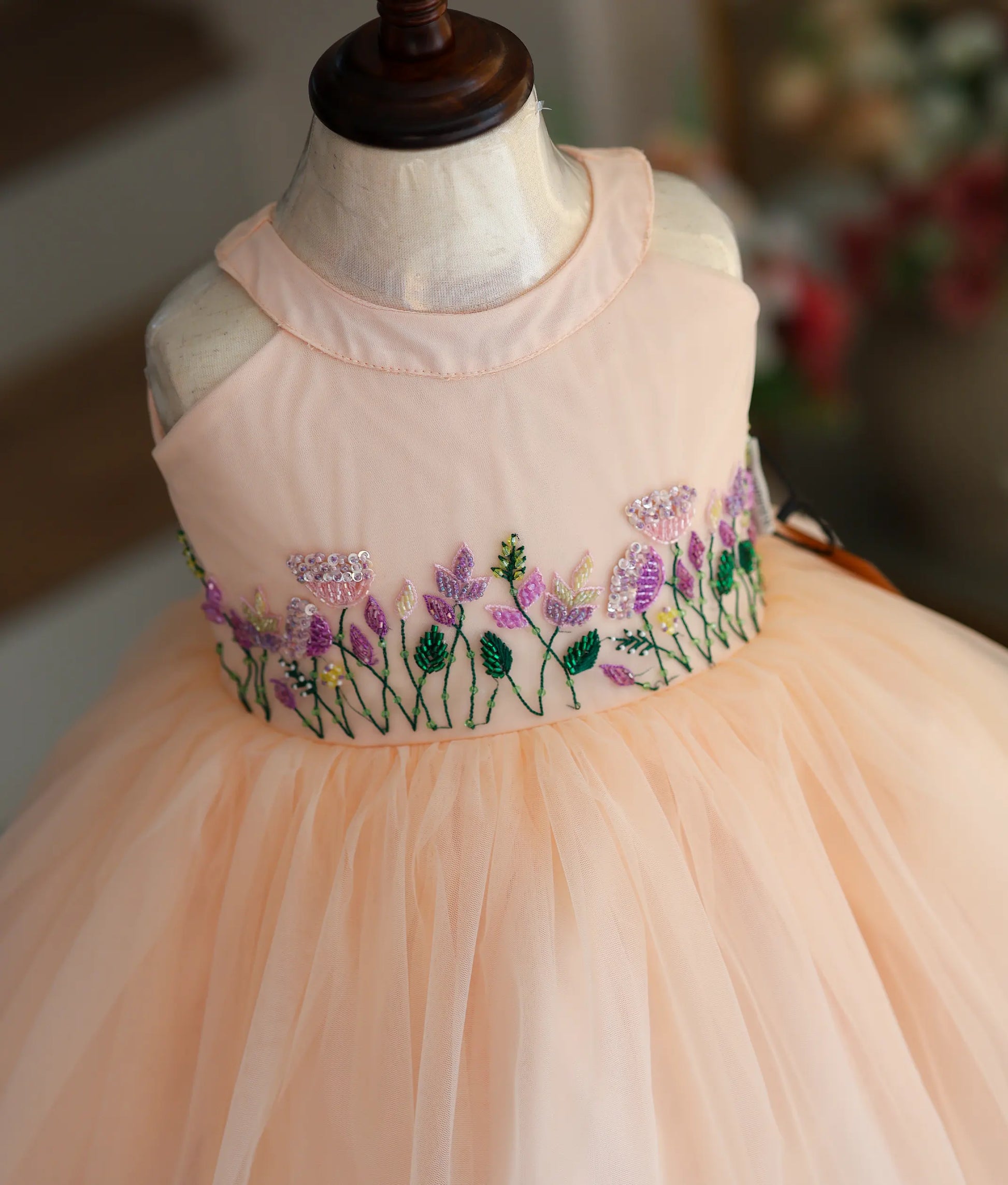 Close-up of the peach frock highlighting the intricate floral embroidery and beadwork on the bodice.
