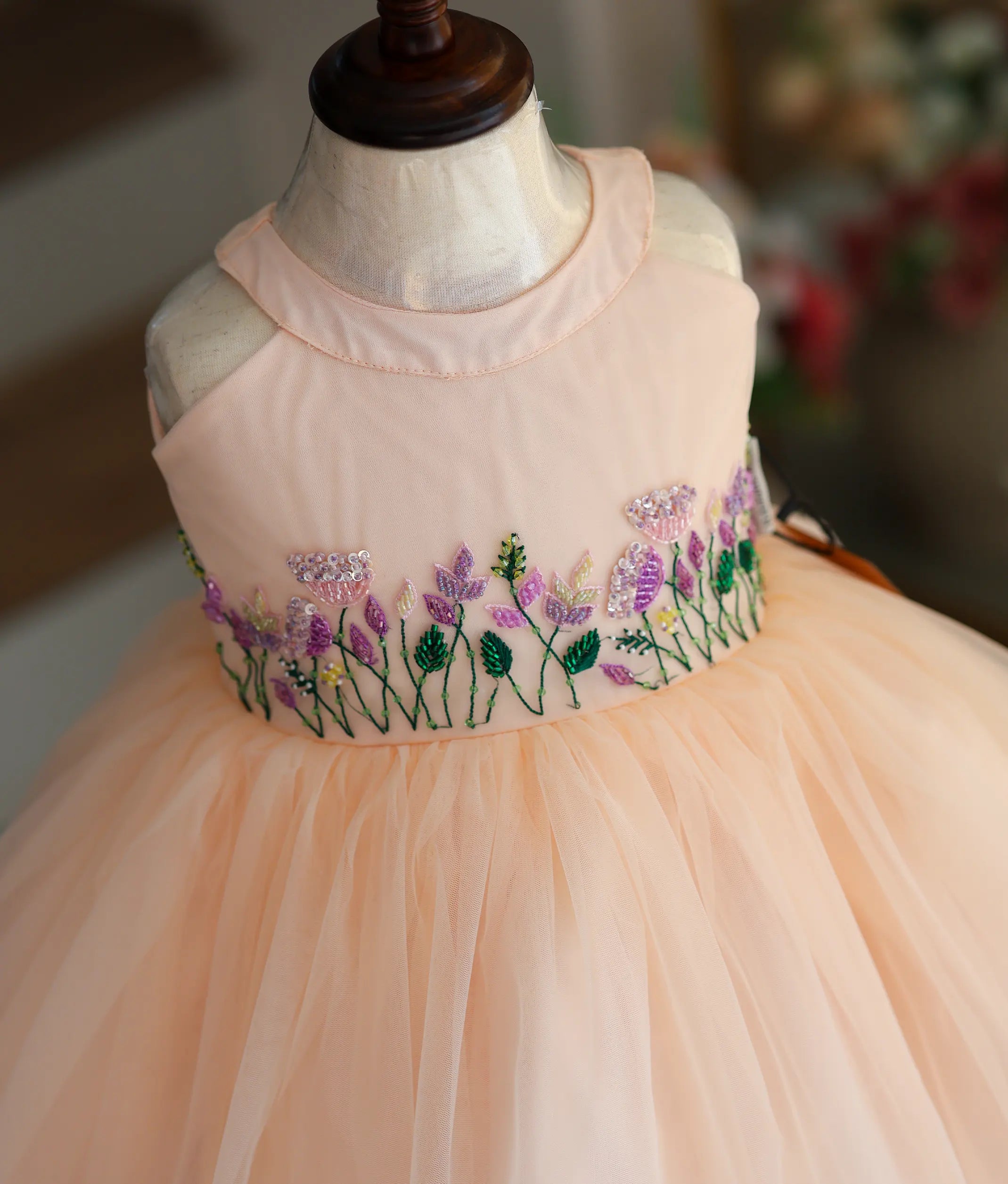 Close-up of the peach frock highlighting the intricate floral embroidery and beadwork on the bodice.