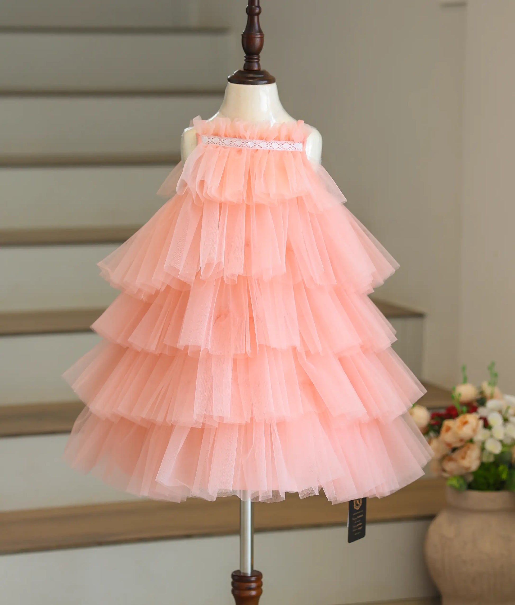 Front view of a peach birthday frock for baby girls featuring a step-pattern tulle net design.