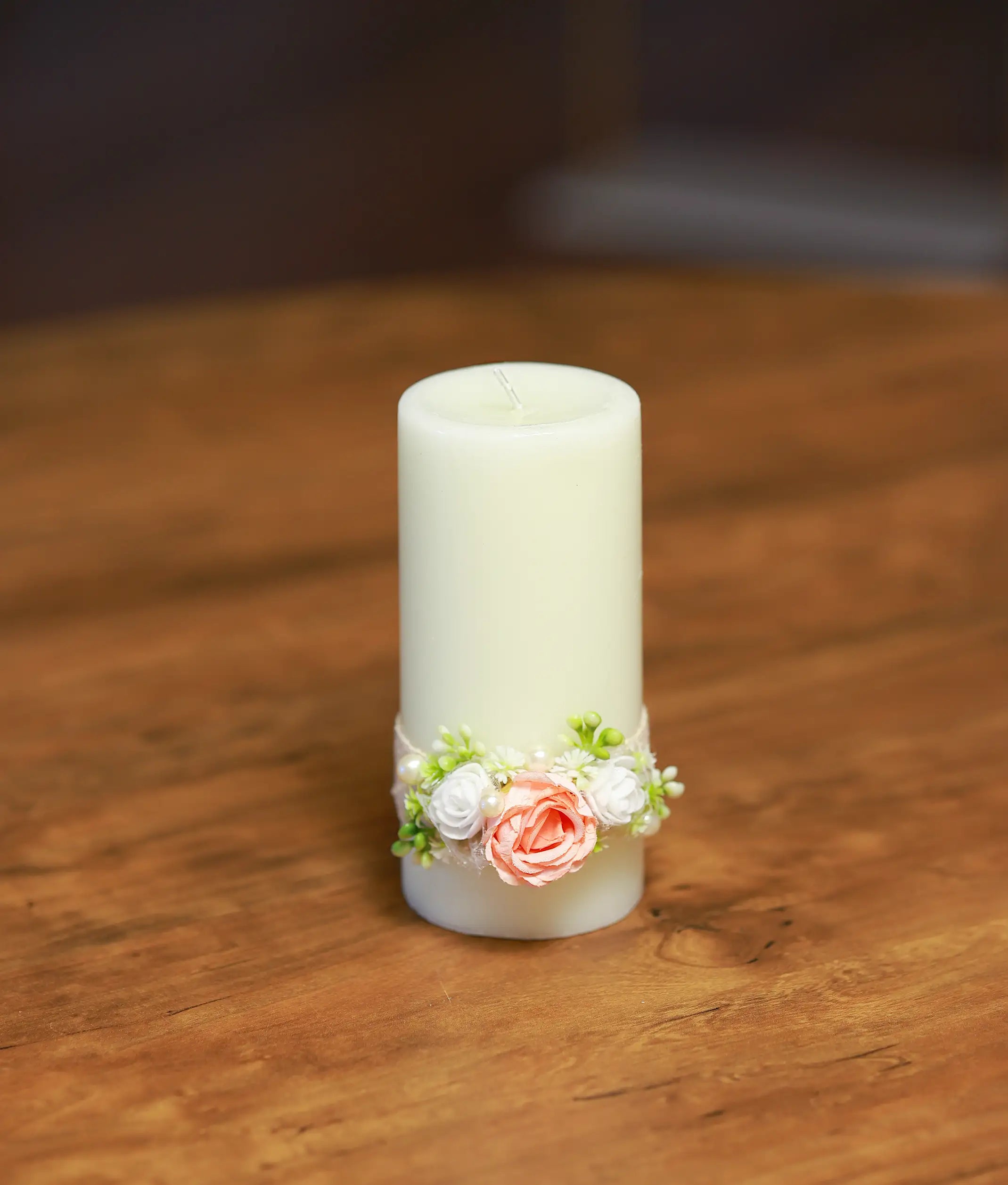 Front view of an ivory decorative baptism candle with a peach rose, white flowers, and lace band