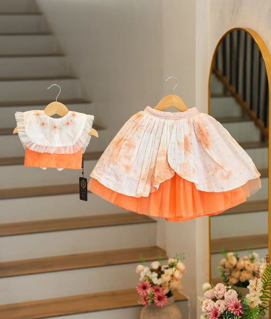 Front view of a baby girl wearing a peach and off-white handworked crop top and full-length layered skirt