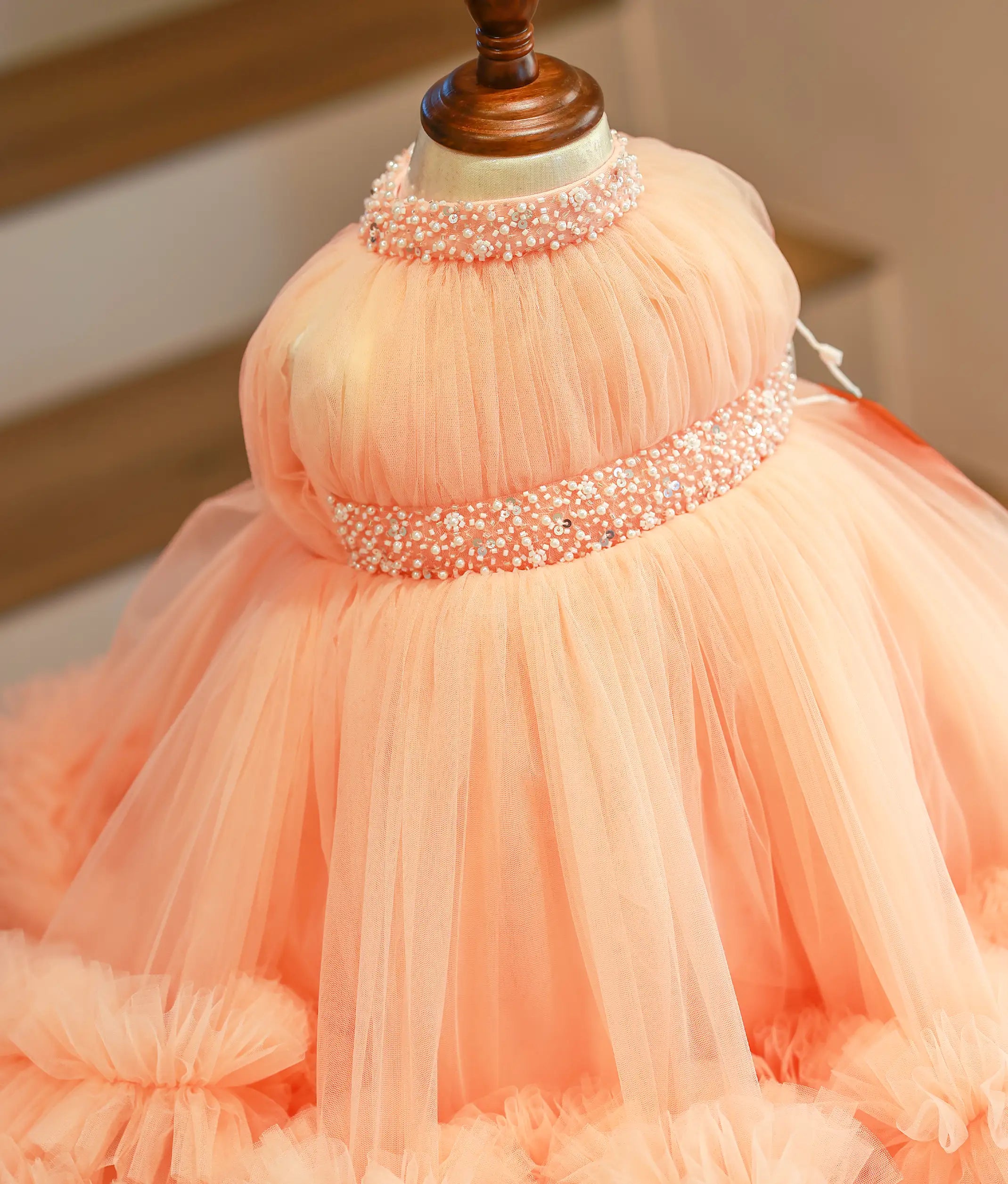 Close-up of the intricate pearl and bead handwork on the waistband and round neckline of the peach gown.