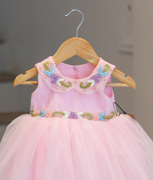 Close-up of the colorful floral handwork, pearl-beaded Peter Pan collar, and pleated fabric.