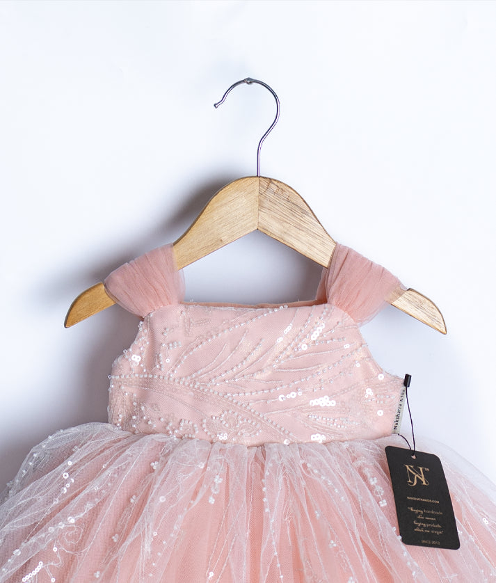 Close up of intricate white sequin leafy pattern on the pink top of the baby girl birthday frock.