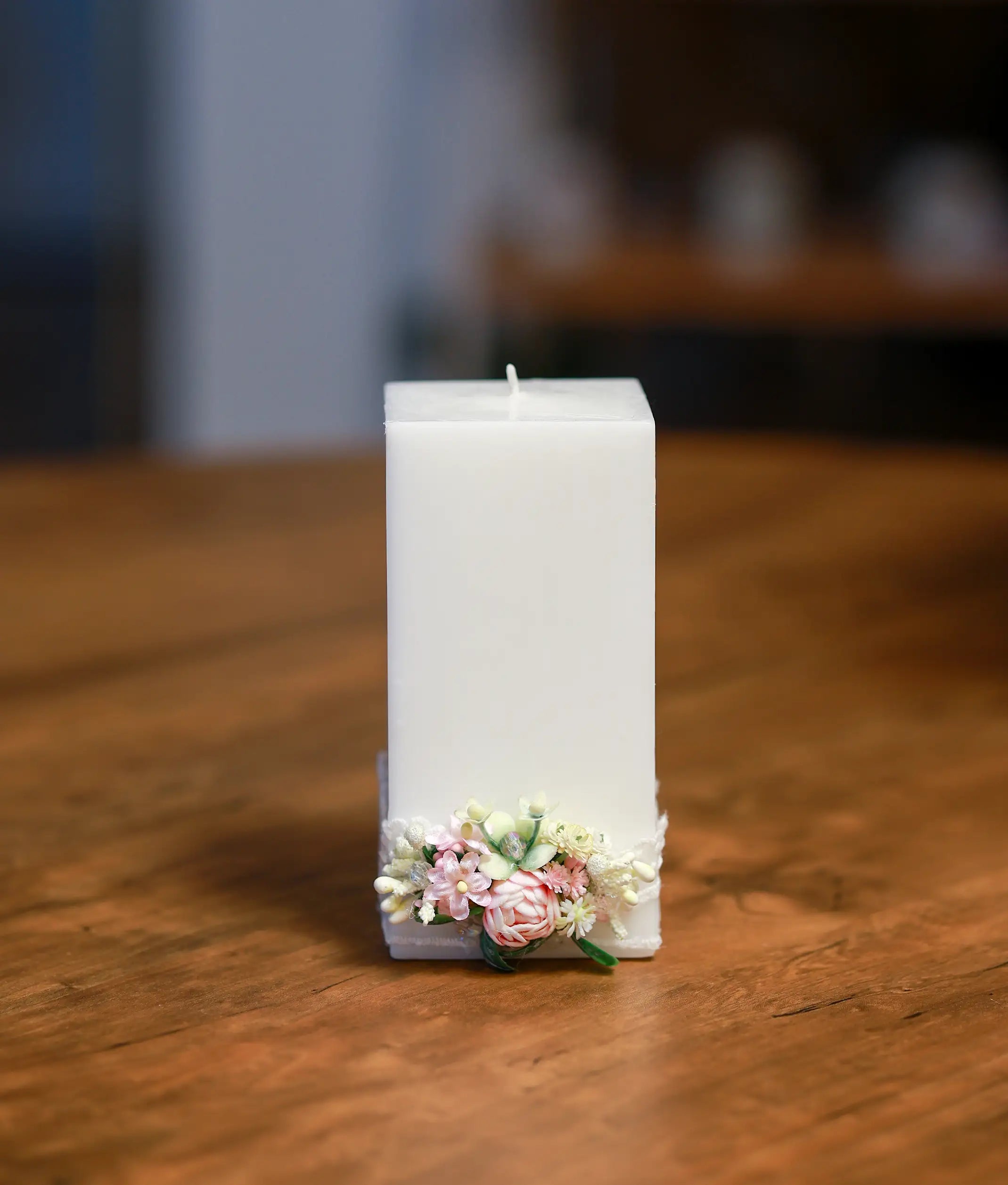 Front view of a white baptism candle decorated with pink blossoms, white flowers, and a pink ribbon