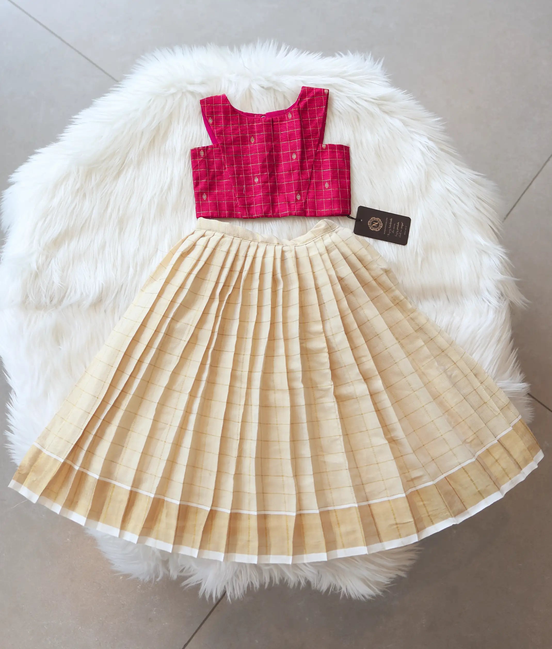 Front view of a girls' pink skirt and top set with checked top and kasavu skirt.