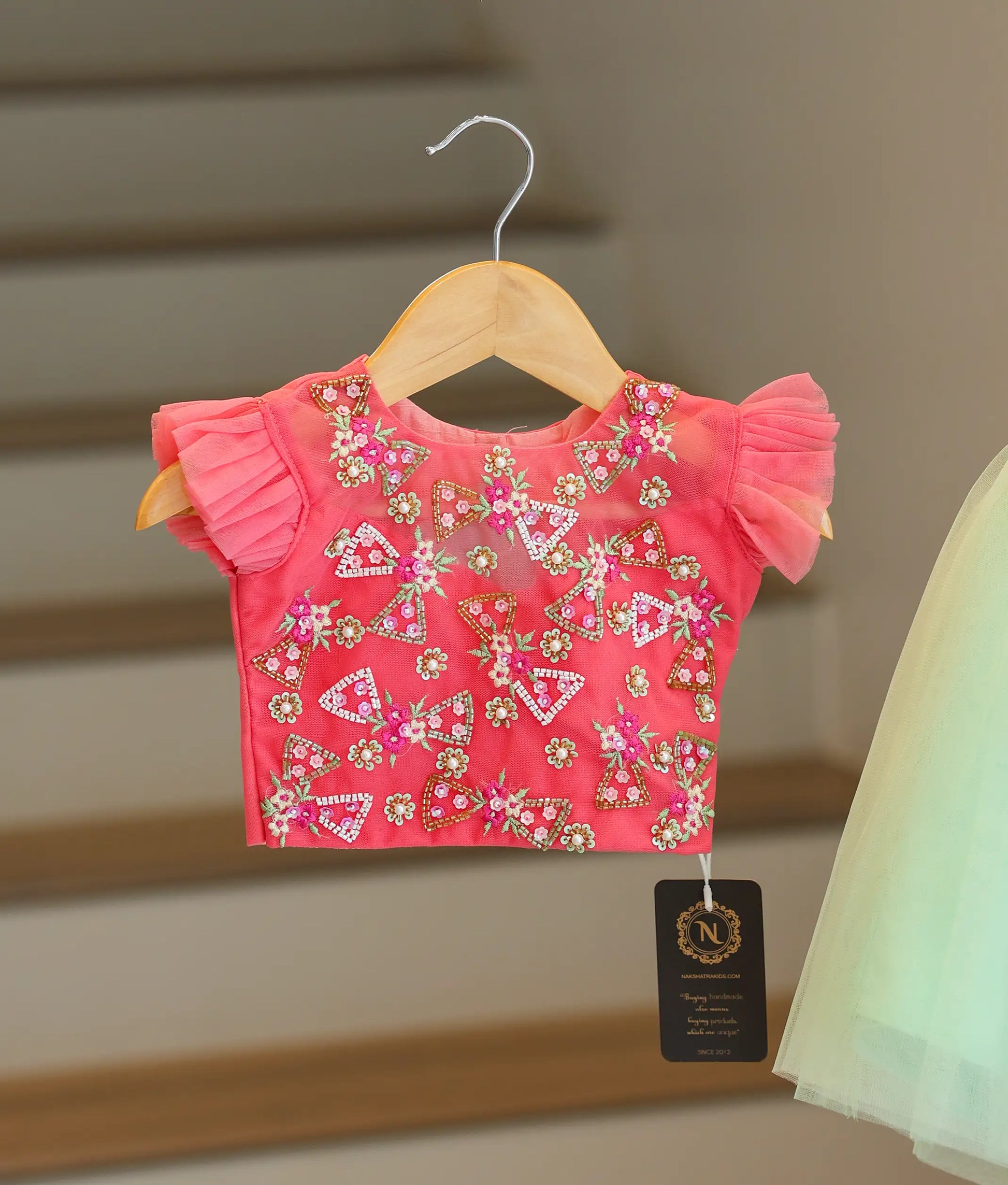Close-up of the pink crop top showing the detailed floral handwork and pretty ruffled sleeves