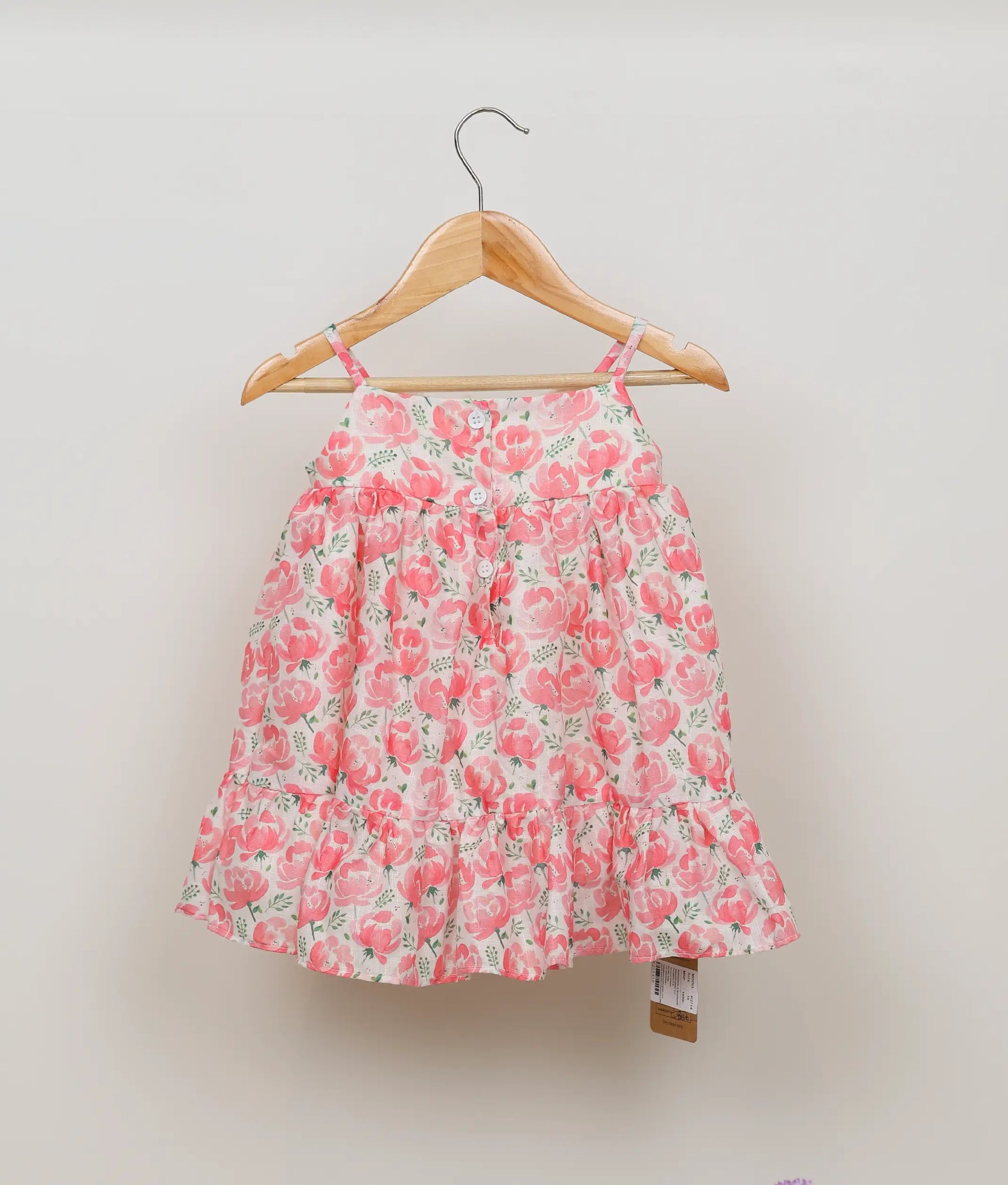 Back view of pink floral-printed cotton christmas frock against plain background