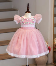 Front view of a pink net frock with puff sleeves and floral handwork.