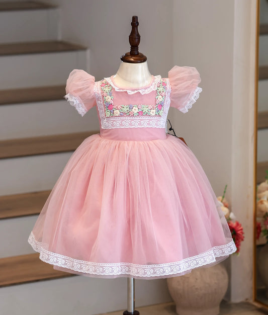 Front view of a pink net frock with puff sleeves and floral handwork.