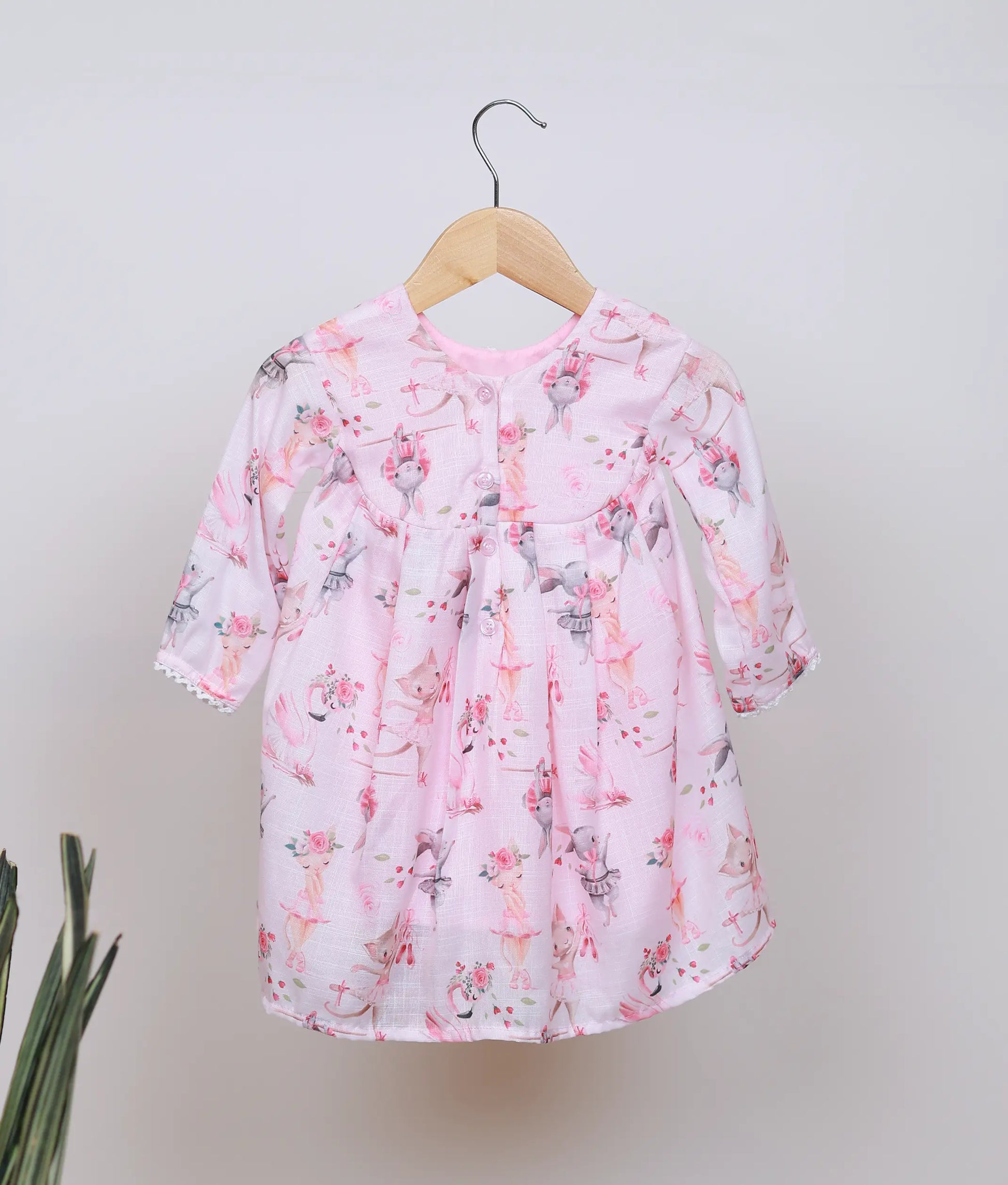 Back view of the pink printed baby girl frock, showing the button closure at the neck and the full sleeves.