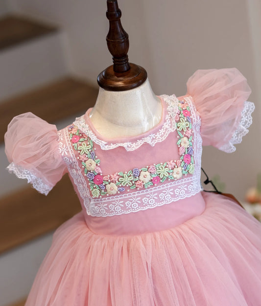 Close-up of the colorful floral handwork and white lace on the pink bodice.