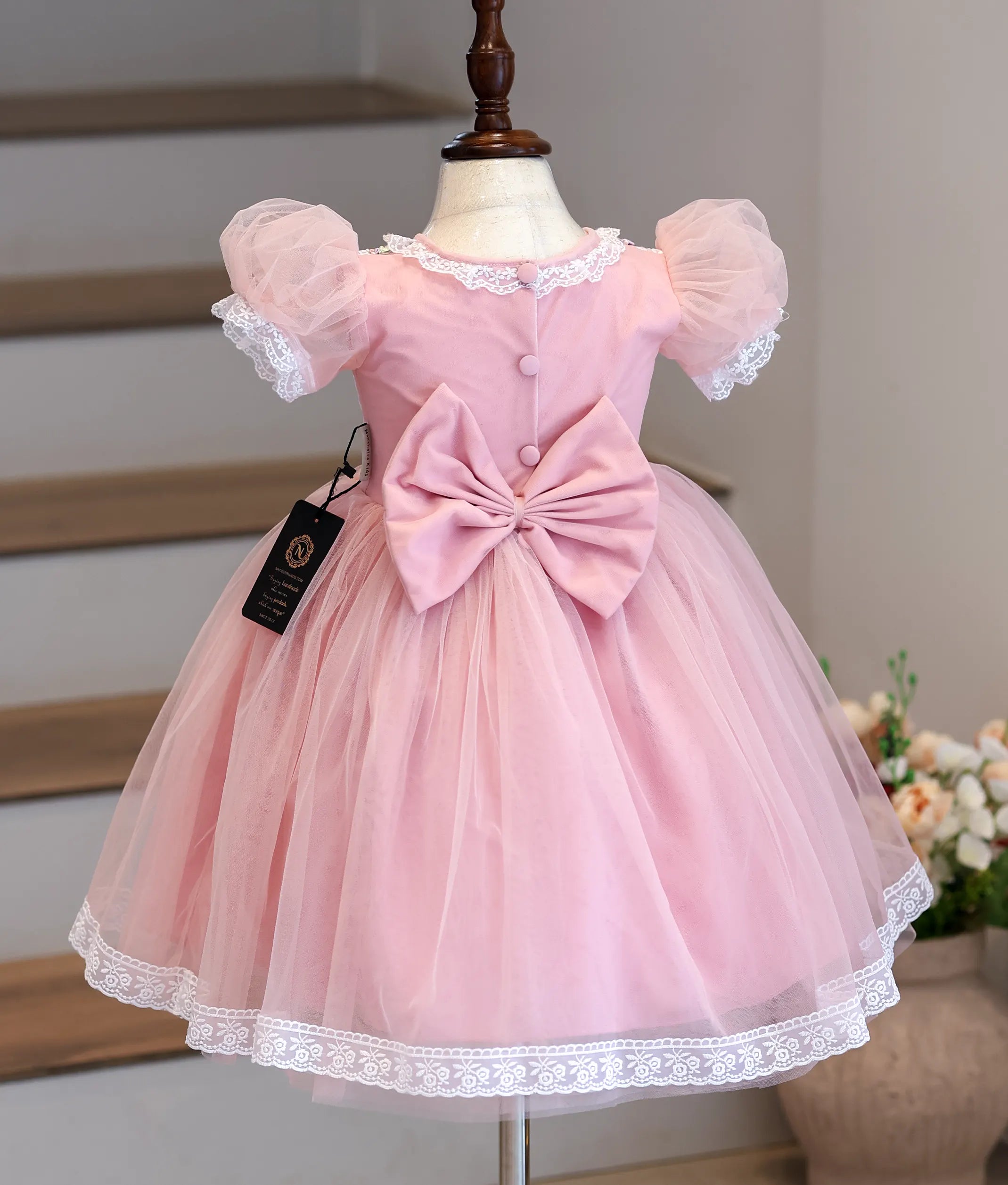 Back view of the pink frock showing the large bow and button opening.
