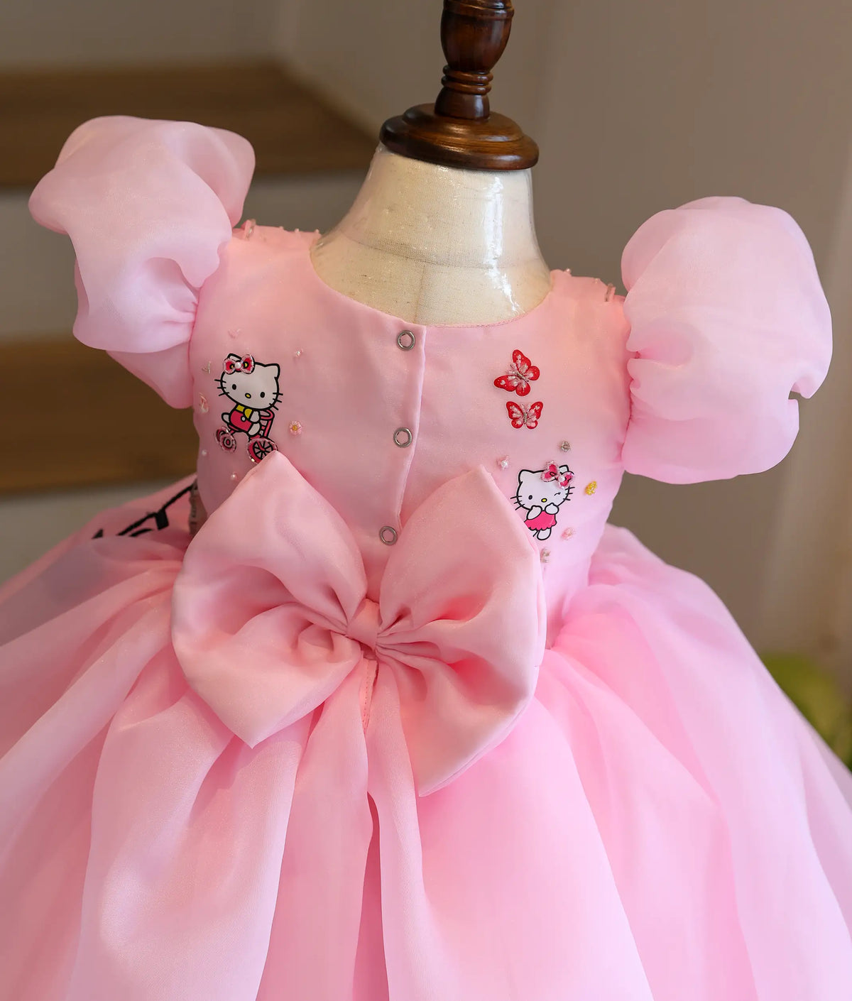 Close-up back view of Hello Kitty frock showing the back button closure and big organza bow.