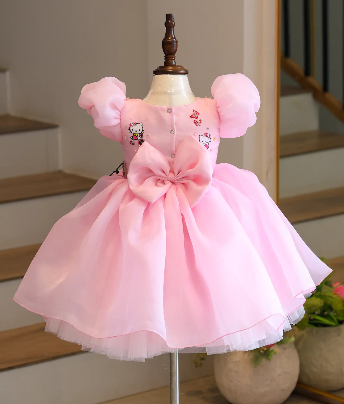 Back view of pink Hello Kitty-themed organza frock showing back buttons and big statement bow.