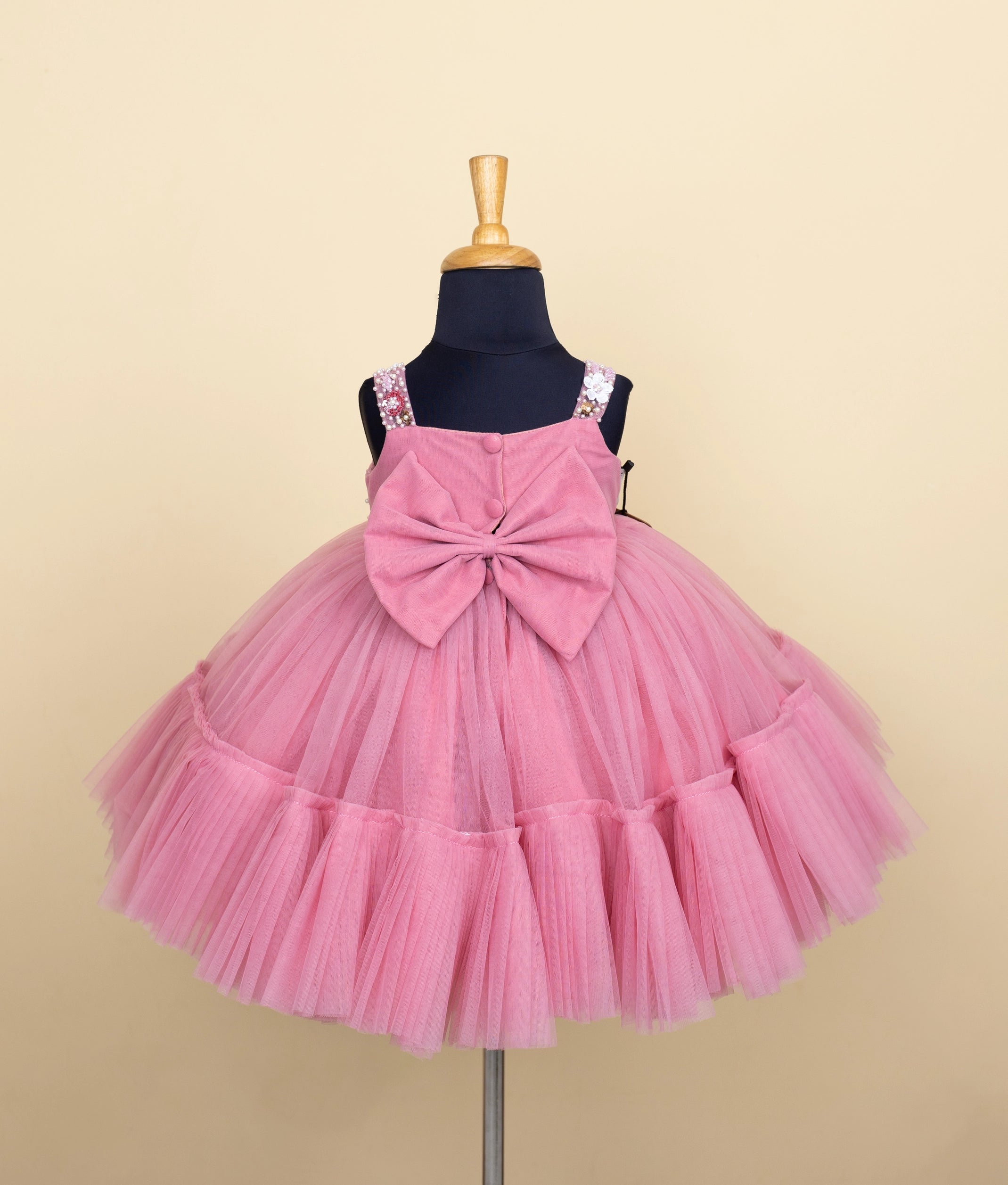 Back view of toddler girl’s pink party wear frock with tulle layers and floral details