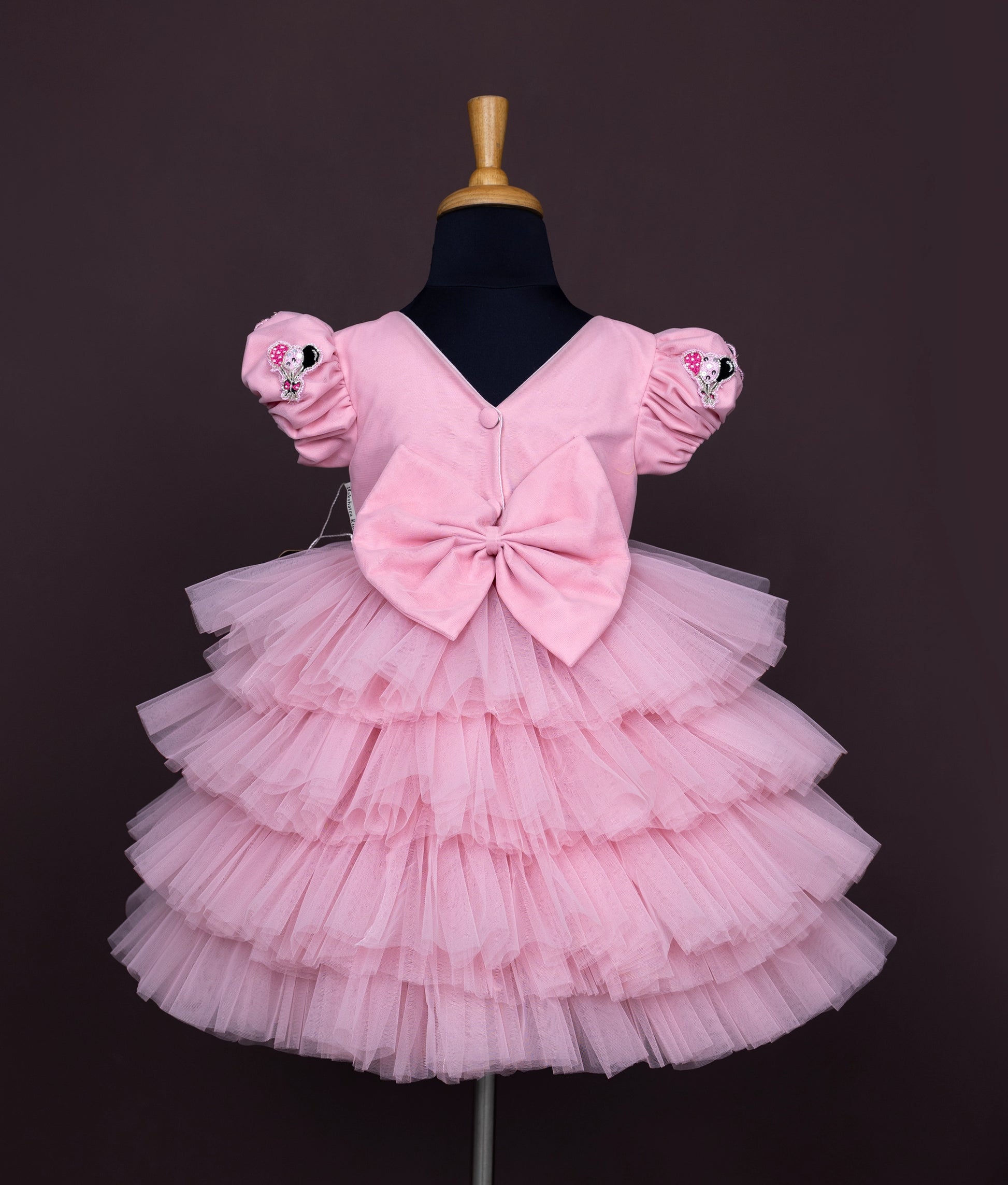 Back view of a pink baby girl dress with puff sleeves, Minnie Mouse sequin work, and a layered net tulle skirt.





Ask ChatGPT
