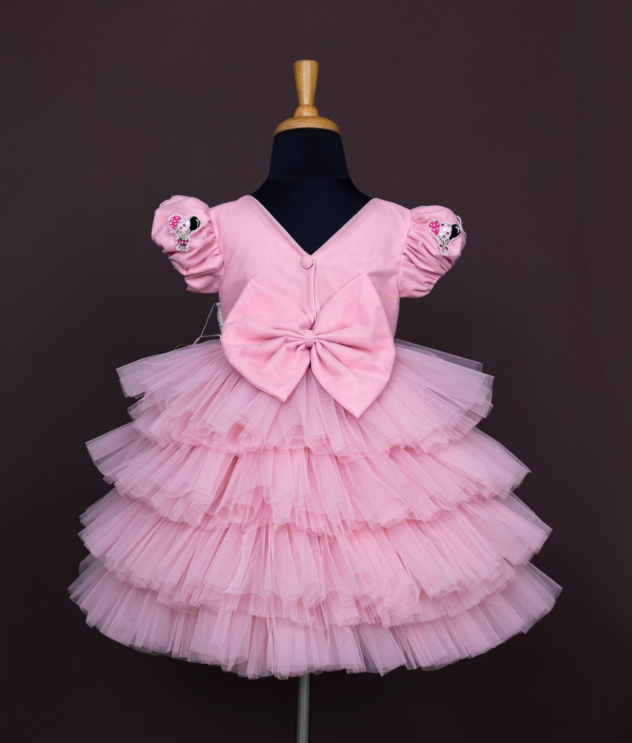 Back view of a pink baby girl dress with puff sleeves, Minnie Mouse sequin work, and a layered net tulle skirt.





Ask ChatGPT
