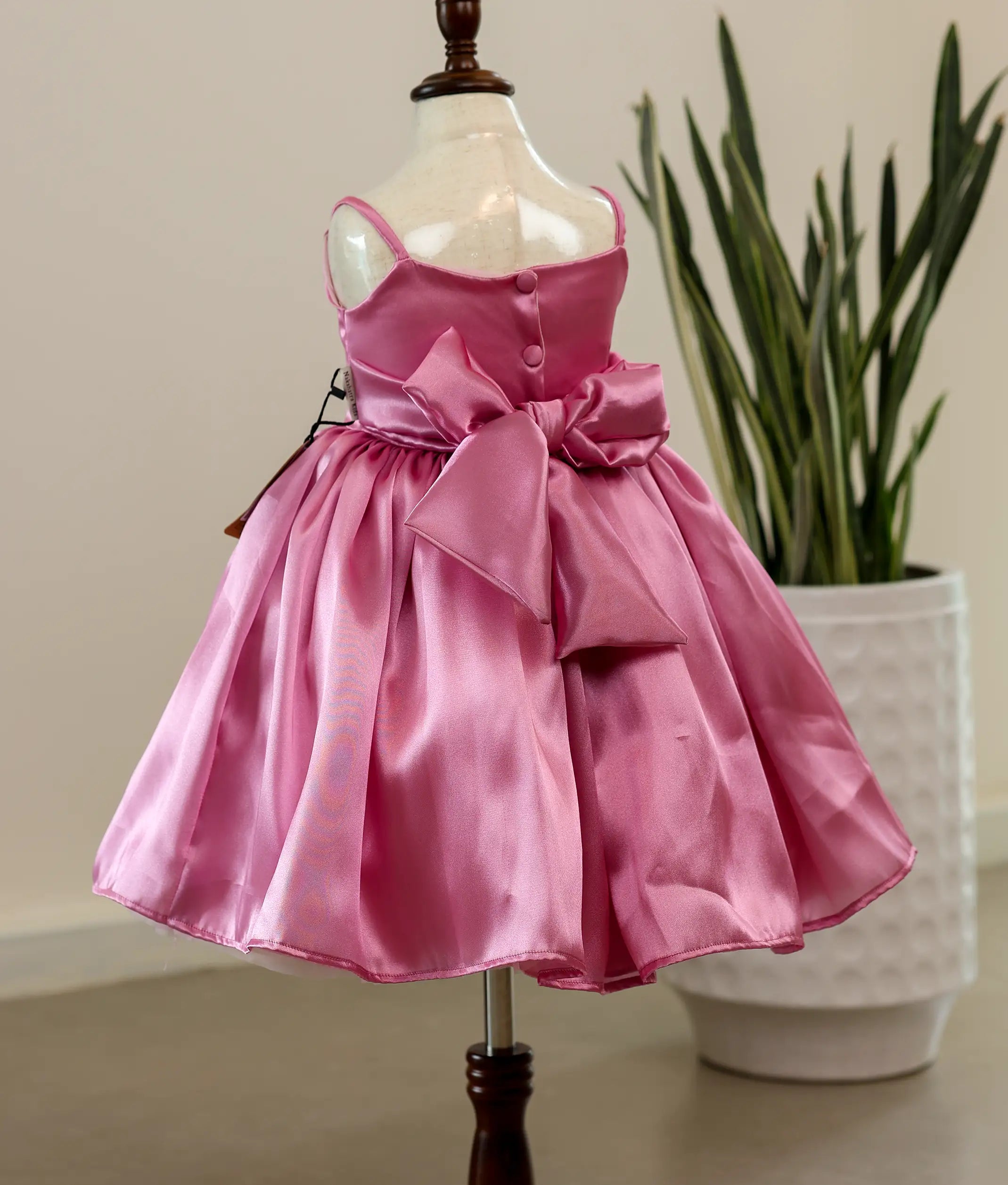 Back view of pink rafaella birthday frock showing the square-neckline with show button and elegant tie closure