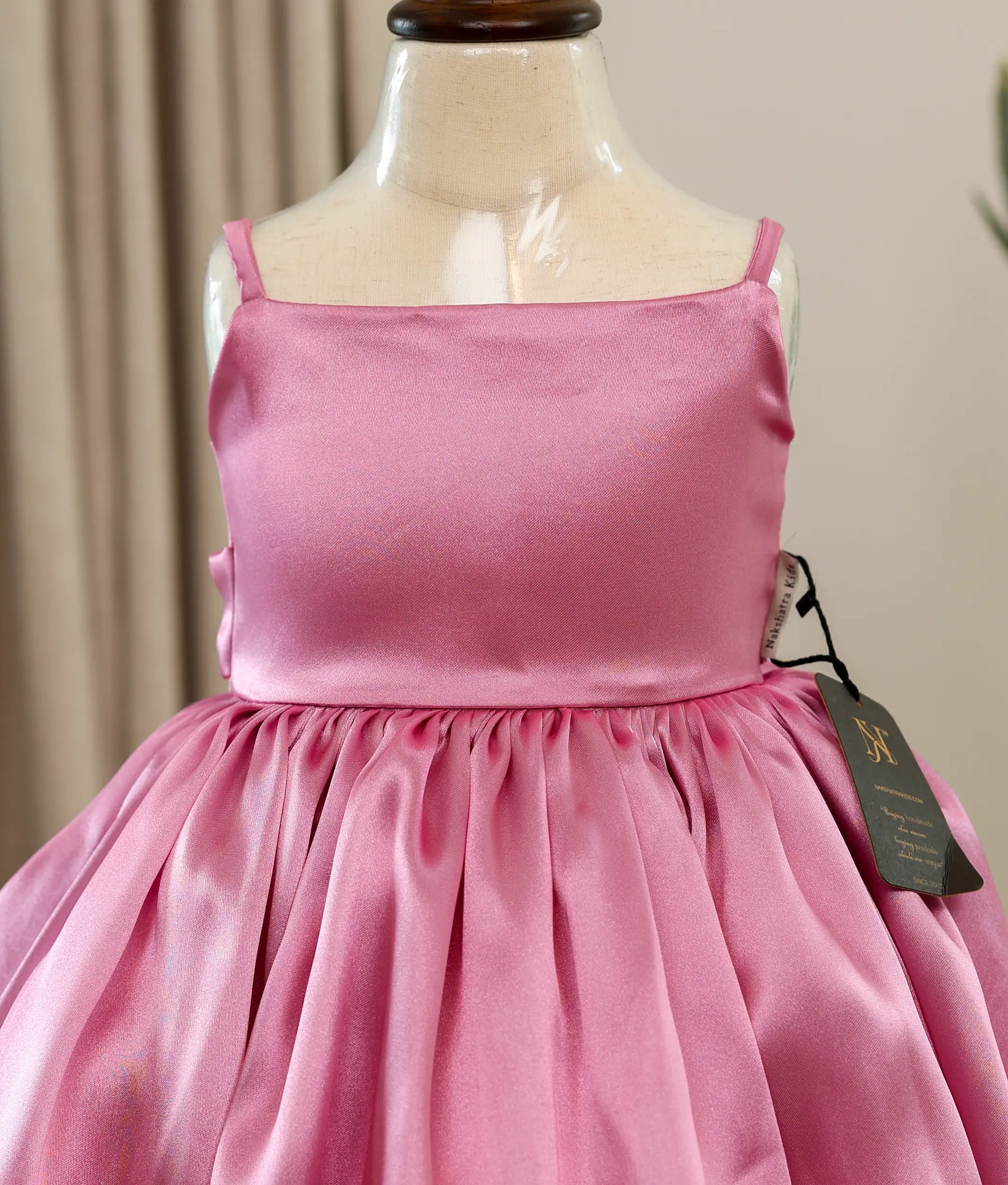 Close-up of the lustrous pink rafaella fabric and clean square-neck yoke detailing on the birthday dress